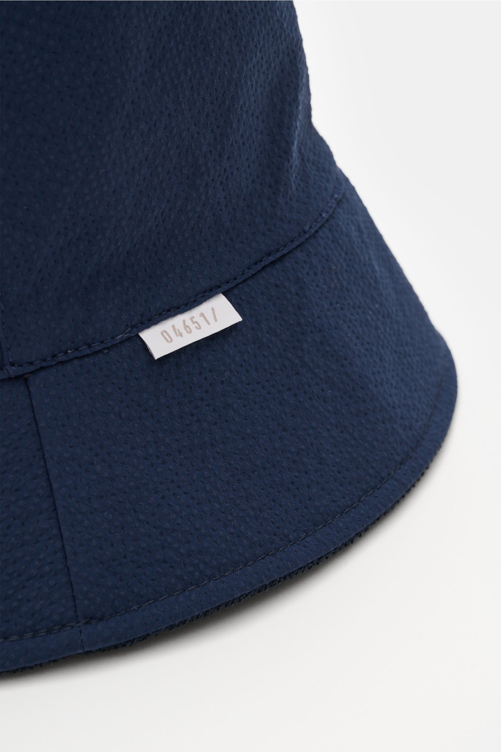 Nahaufnahme des 04651/ A trip in a bag Wende-Frottee Bucket Hat navy mit schmaler Krempe, elastischem Baumwoll-Frottee und kleinem Weblabel, von schräg oben fotografiert.