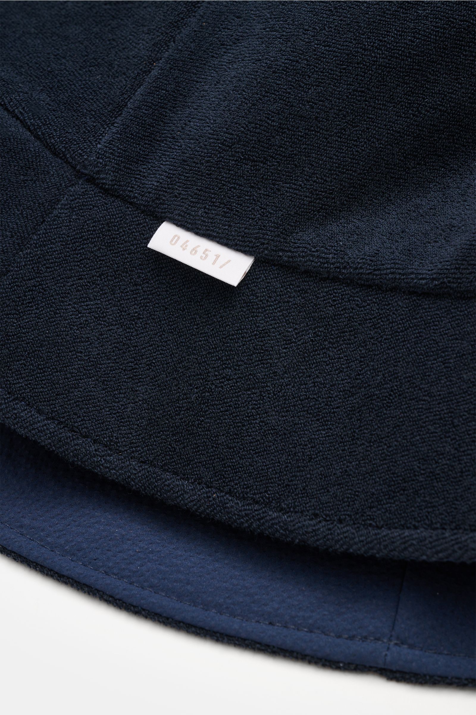 04651/ A trip in a bag Wende-Frottee Bucket Hat navy aus elastischem Baumwoll-Frottee mit schmaler Krempe, weichem Griff und kleinem Weblabel, Detailaufnahme von unten.