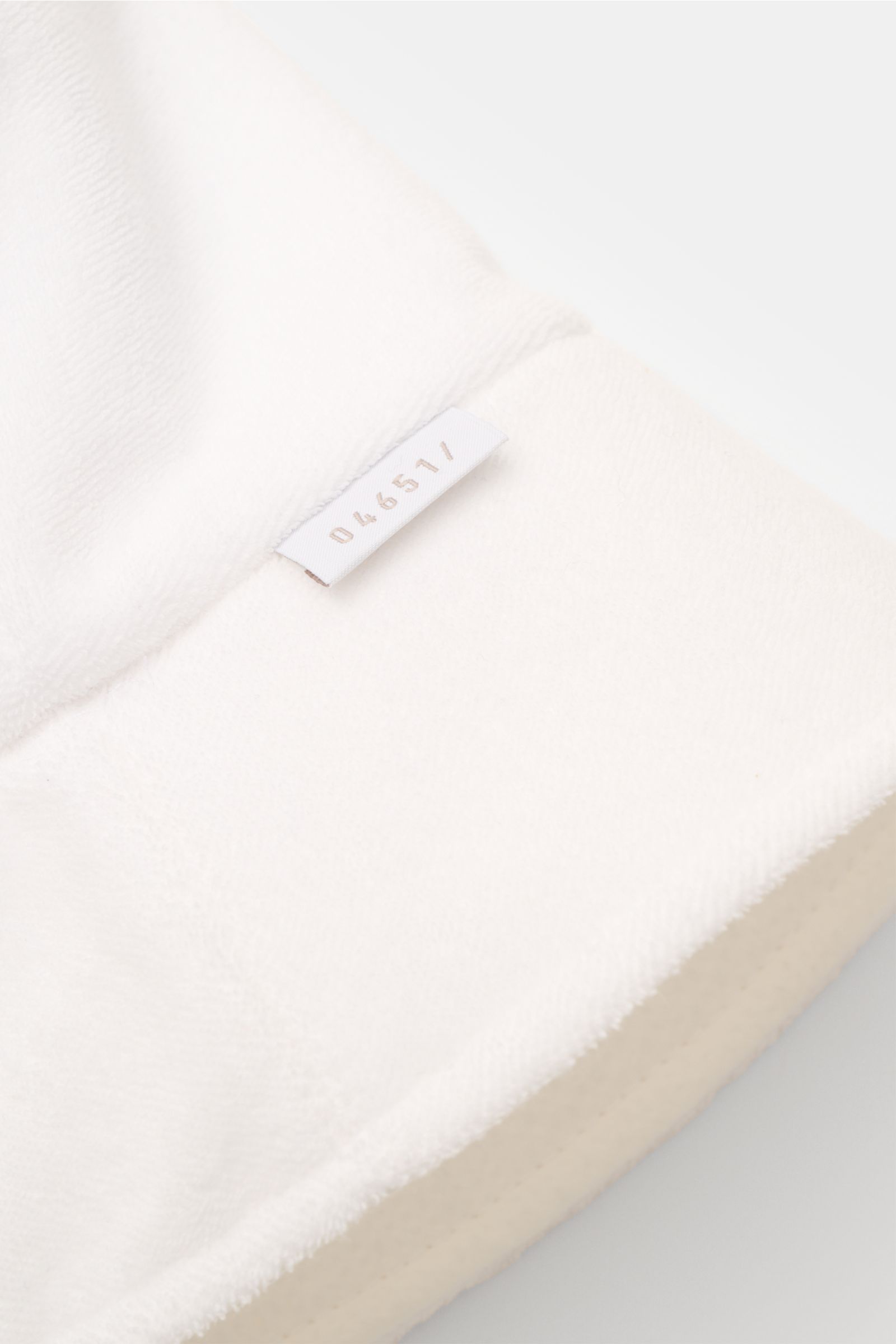 Close-up of the soft white 04651/ A trip in a bag Wende-Frottee Bucket Hat weiß showing the elastic cotton terry fabric, narrow brim, and small label, photographed from a top angle.

Description: Vielseitiger Urlaubsbegleiter: Der Bucket Hat von 04651/