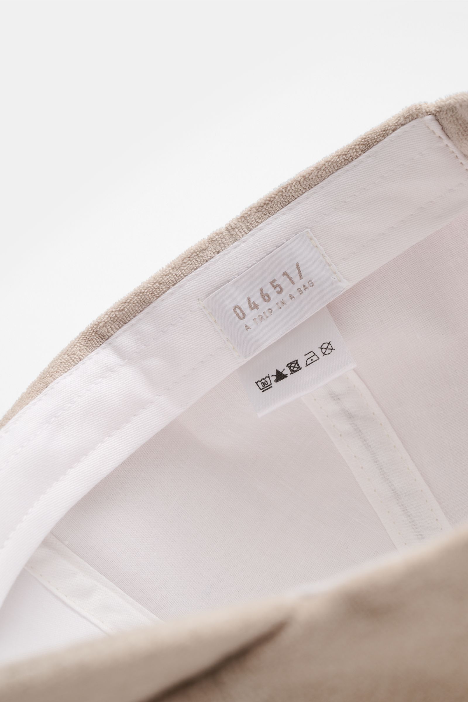 Close-up interior view of the 04651/ A trip in a bag Terry baseball cap 'Terry' beige showing white inner lining, label, and stitching. Spring awakening: This stylish baseball cap in soft terry by label 04651/ A TRIP IN A BAG offers good protection and ca