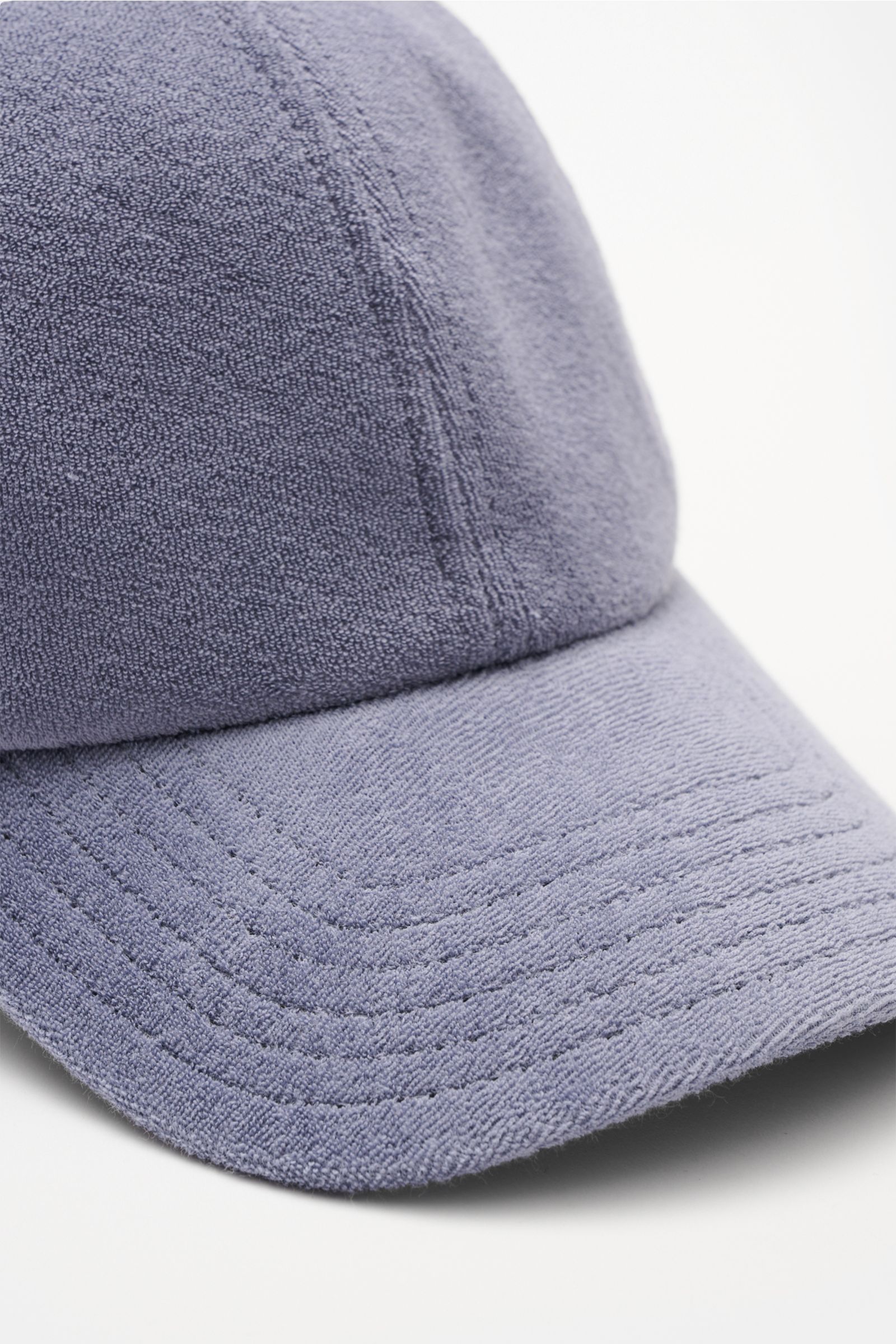 Close-up front-side view of the 04651/ A trip in a bag Terry baseball cap 'Terry' smoky blue in soft cotton terry fabric with six-panel style and adjustable closure, offering a soft feel and sporty yet trendy preppy look. Spring awakening: This stylish ba