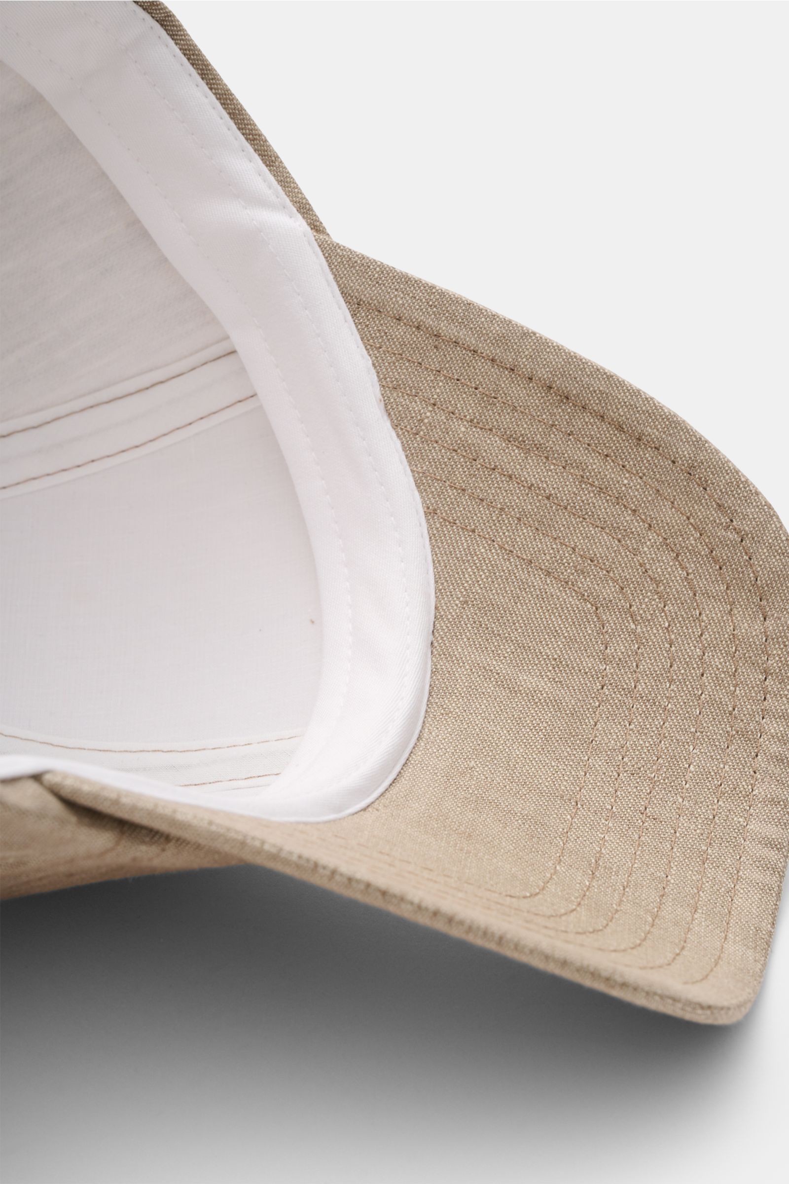 Close-up view from below of the 04651/ A trip in a bag Baseball cap 'Linen' taupe mottled showing the taupe mottled pure linen brim and white inner lining, combining lightweight natural fibres with a sporty aesthetic in a six panel style with adjustable c