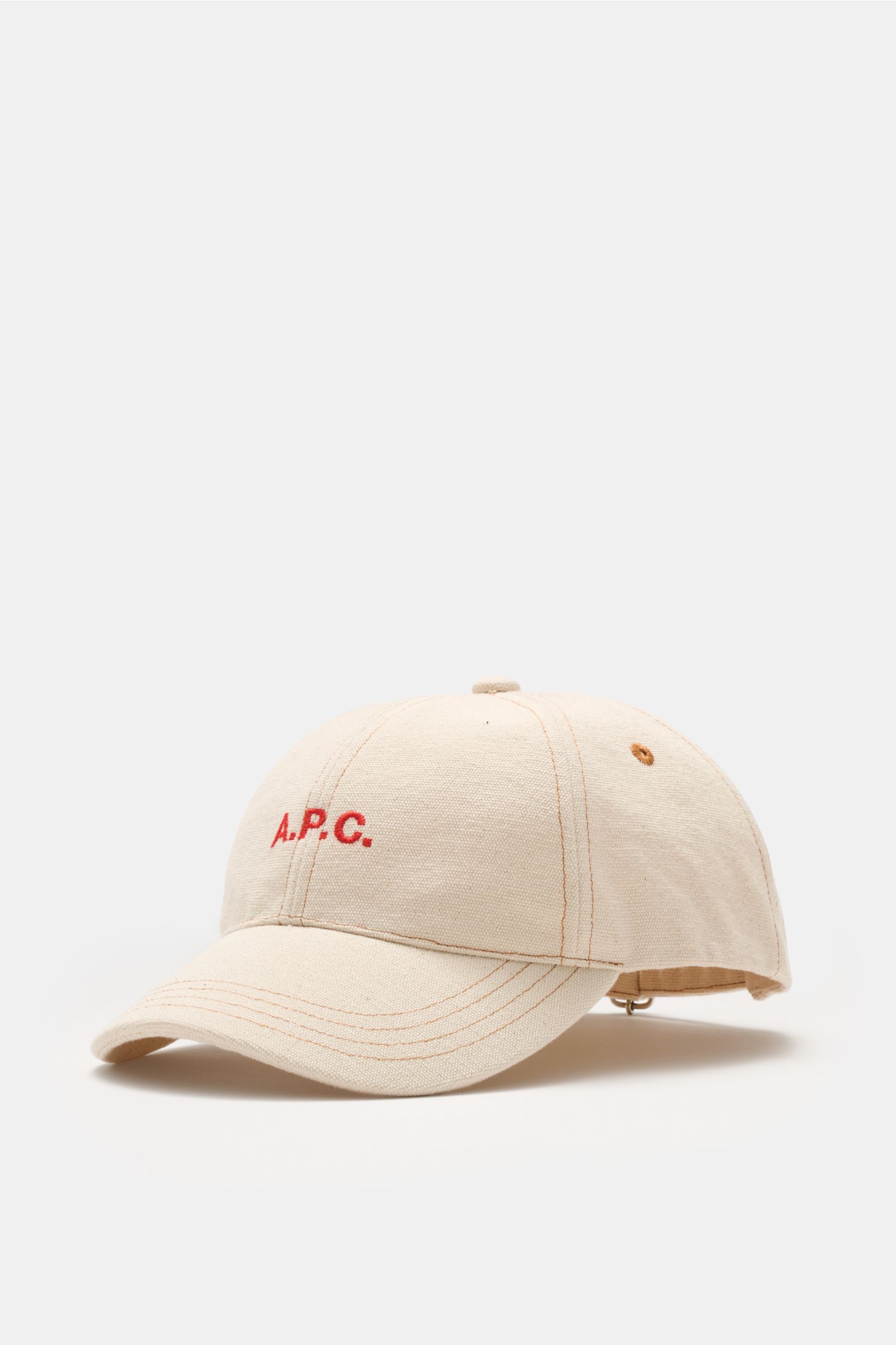 A.P.C. Baseball-Cap 'Charlie' creme aus robustem Baumwoll-Canvas, Six-Panel-Design, rotes tonales Logo, verstellbarer Verschluss, seitliche Perspektive.