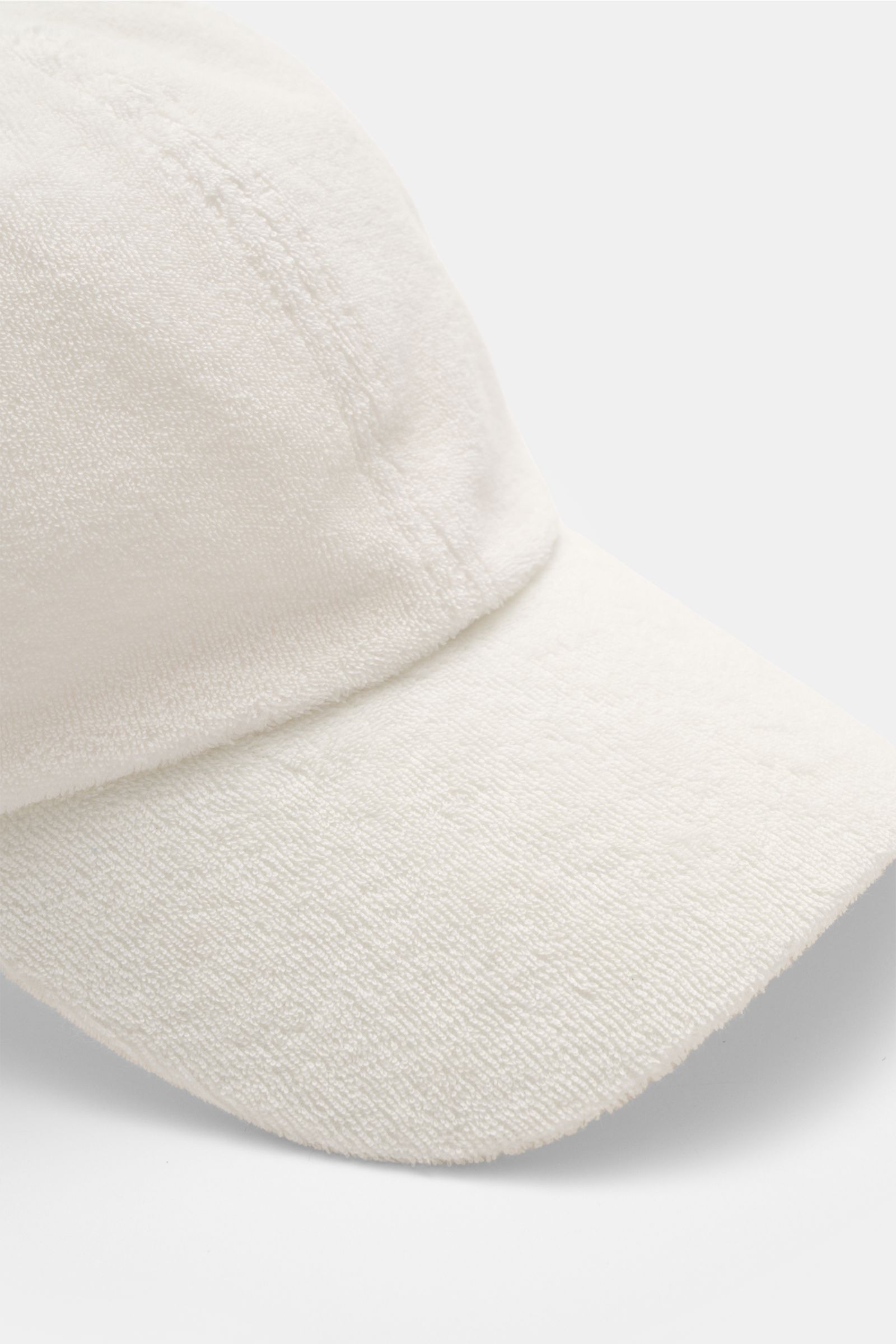 Nahaufnahme der cremefarbenen 04651/ A trip in a bag Frottee Baseball-Cap 'Terry' im Six-Panel-Stil mit weichem Griff, verstellbarem Verschluss, fotografiert von oben vorne.