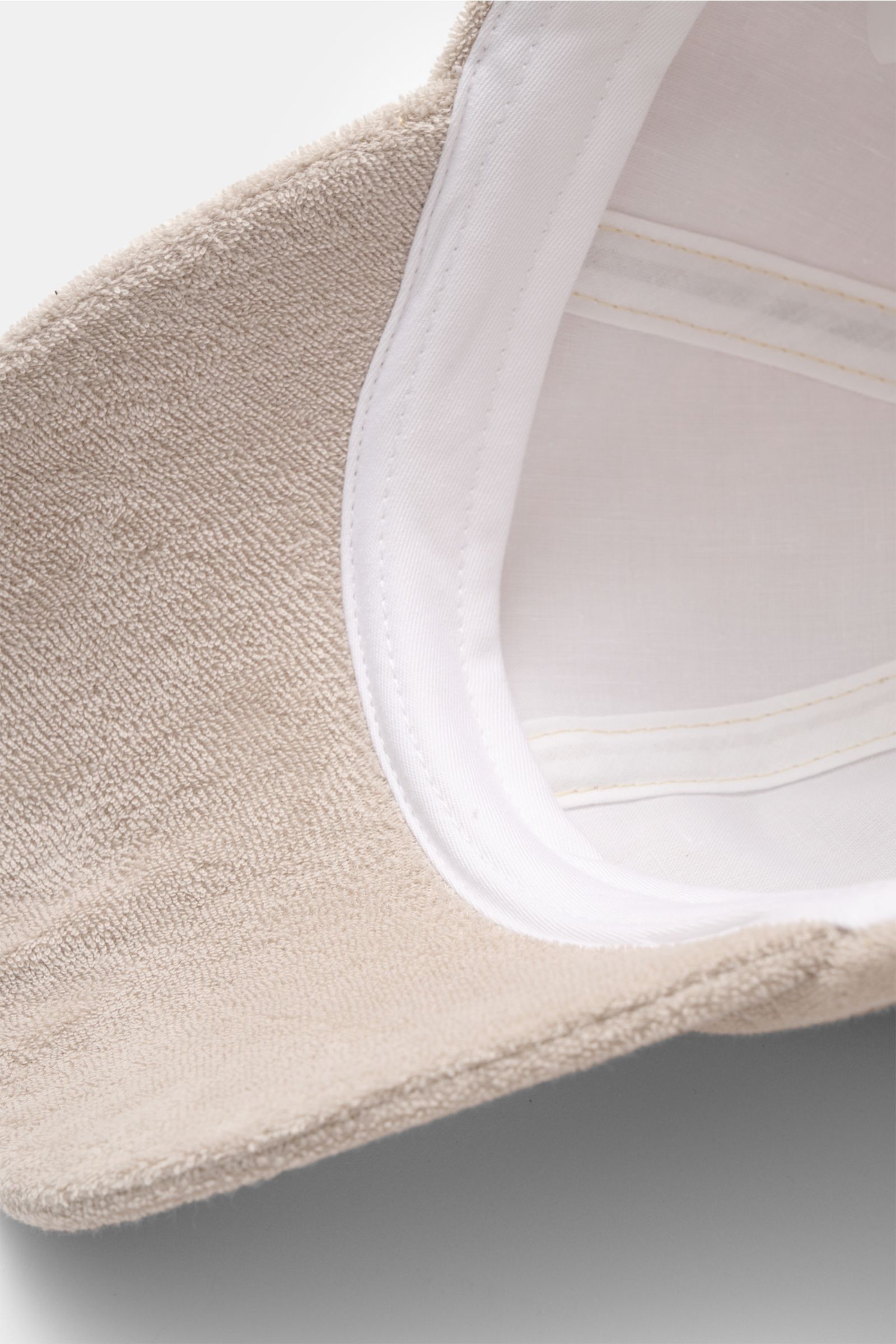 Close-up view from the inside of the beige 04651/ A trip in a bag Terry baseball cap 'Terry' showing soft cotton terry fabric and white inner lining.

Spring awakening: This stylish baseball cap in soft terry from the label 04651/ A TRIP IN A BAG offer