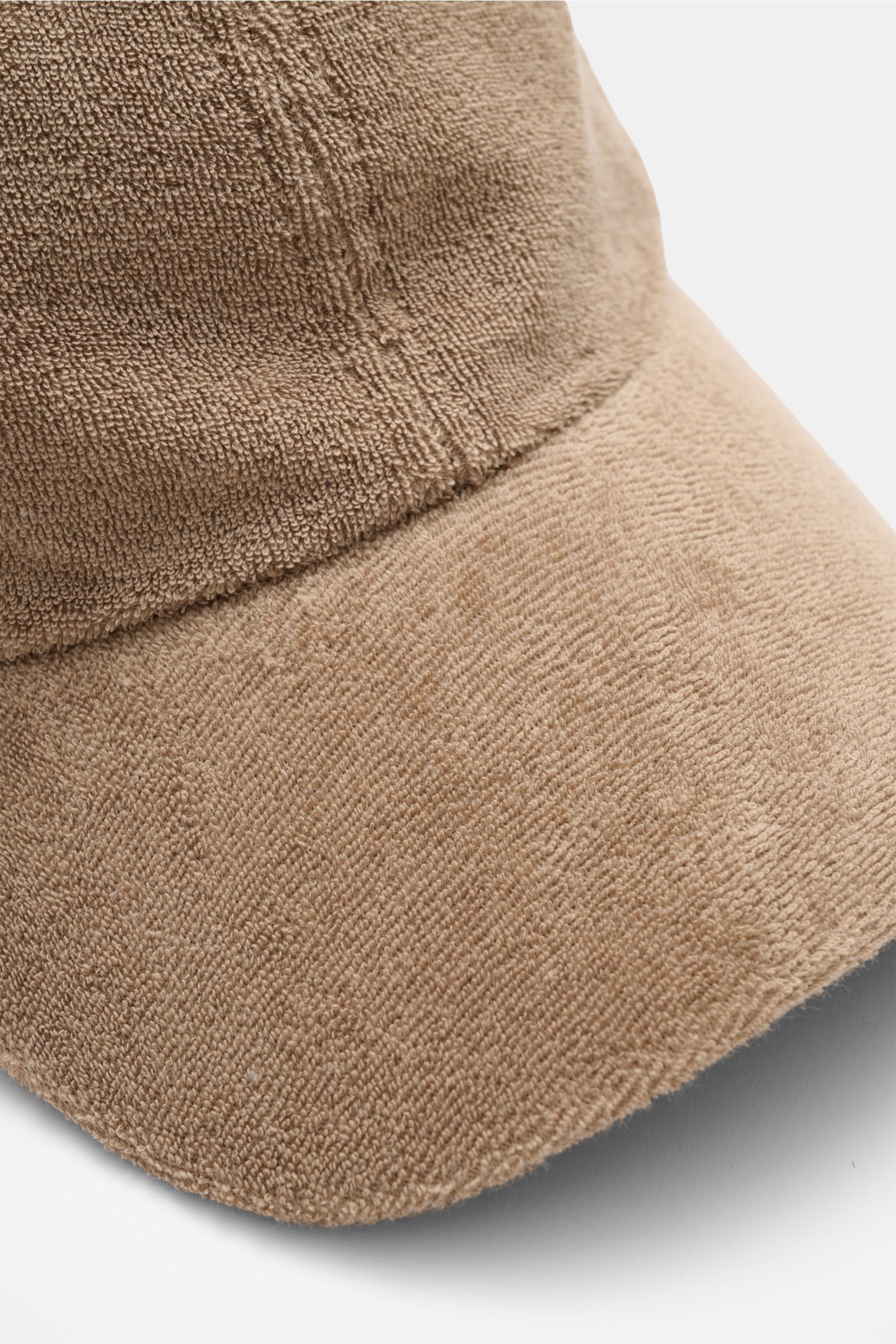 Nahaufnahme der 04651/ A trip in a bag Frottee Baseball-Cap 'Terry' taupe aus Baumwolle mit weichem Griff im Six-Panel-Stil, seitliche Perspektive.