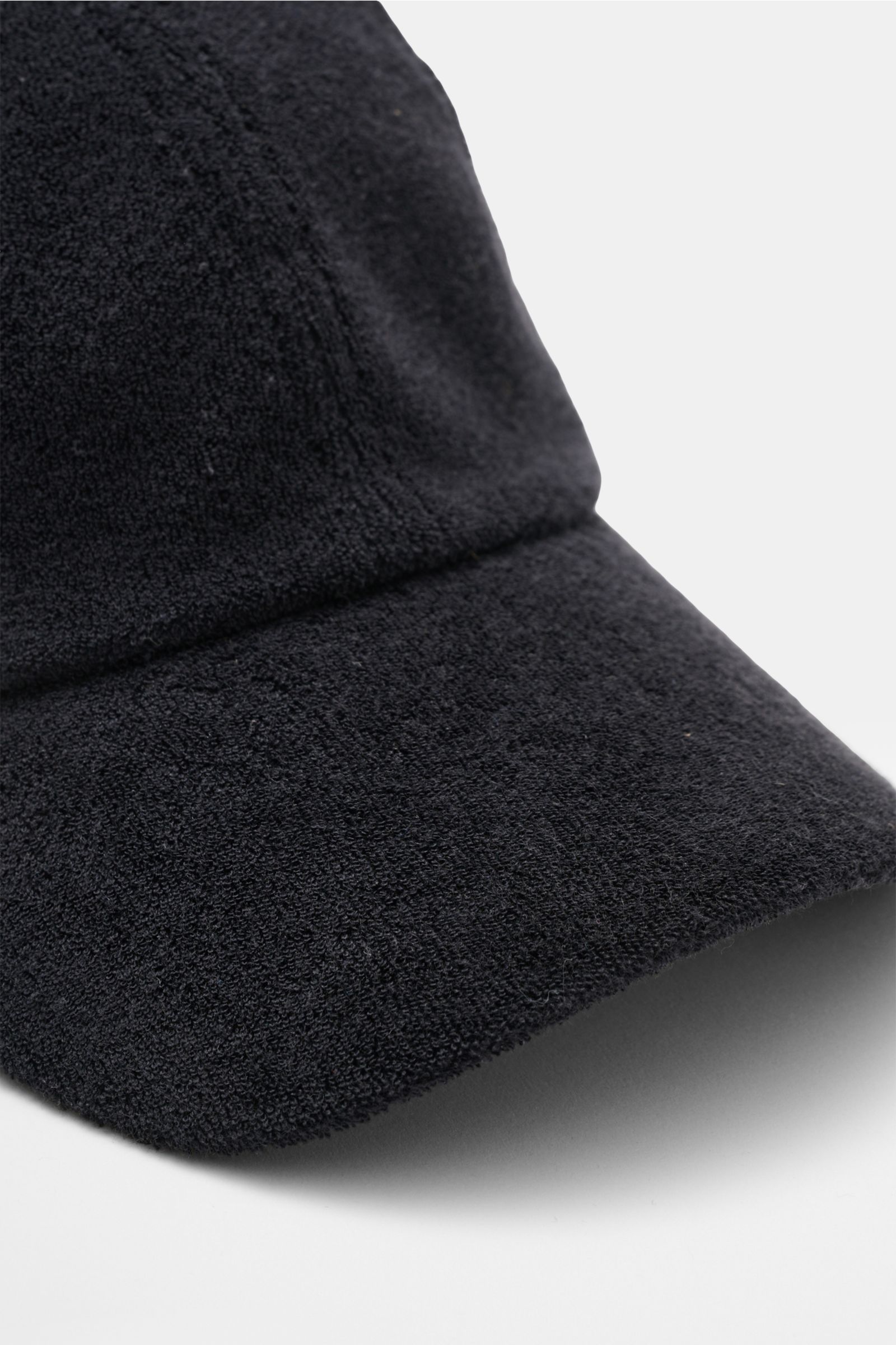 Close-up front-side view of 04651/ A trip in a bag Terry baseball cap 'Terry' black in soft cotton terry, six-panel style with adjustable closure. Spring awakening: This stylish baseball cap in soft terry from the label 04651/ A TRIP IN A BAG offers good 