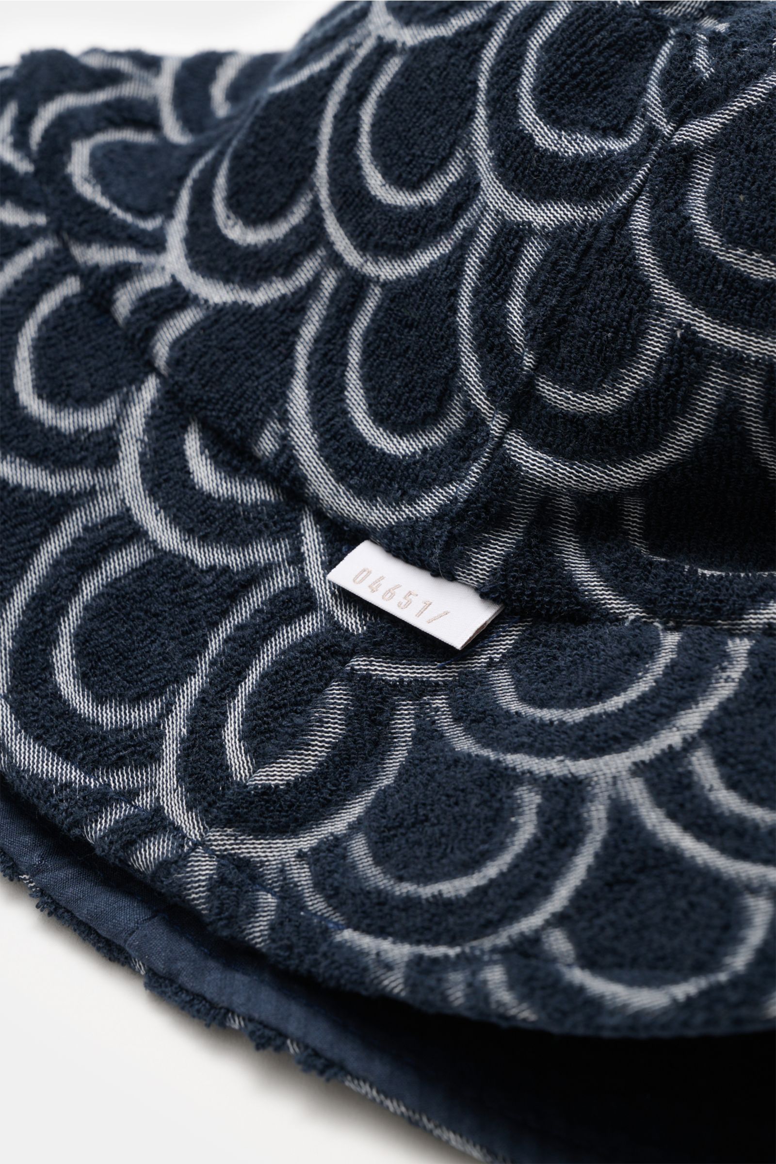 Close-up angled view of the 04651/ A trip in a bag Reversible terry bucket hat navy showing navy cotton terry with white circle pattern and woven label.

Versatile holiday companion: The bucket hat from 04651/ A TRIP IN A BAG, made from cotton terry, o