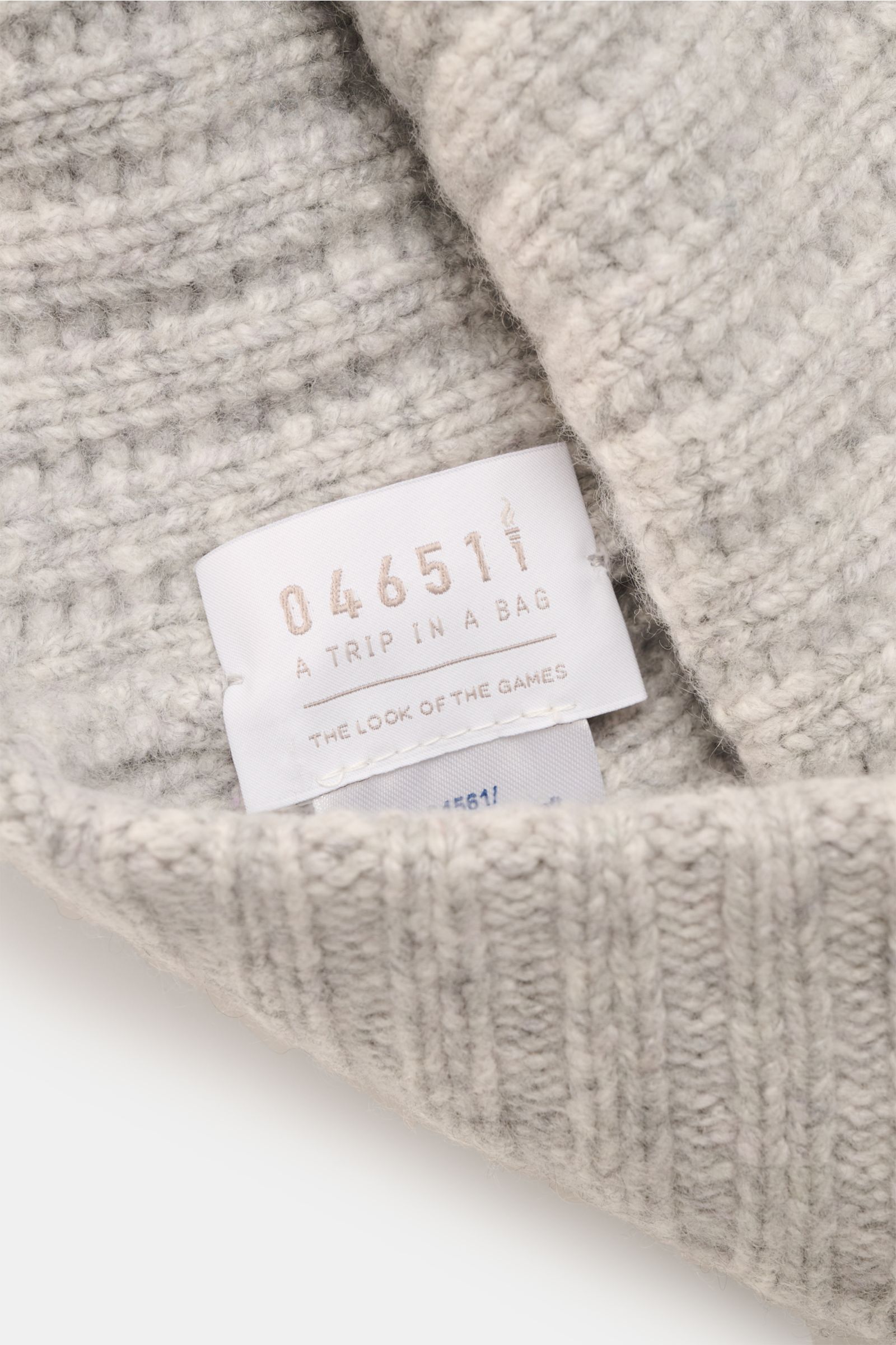 Close-up from above of the 04651/ A trip in a bag Cashmere Mütze hellgrau meliert showing soft, medium-knit patent pattern and wide cuff with brand label.

Luxuriöses Winter-Accessoire: Die edle Cashmere-Mütze aus der ‚Look of the Games‘ C