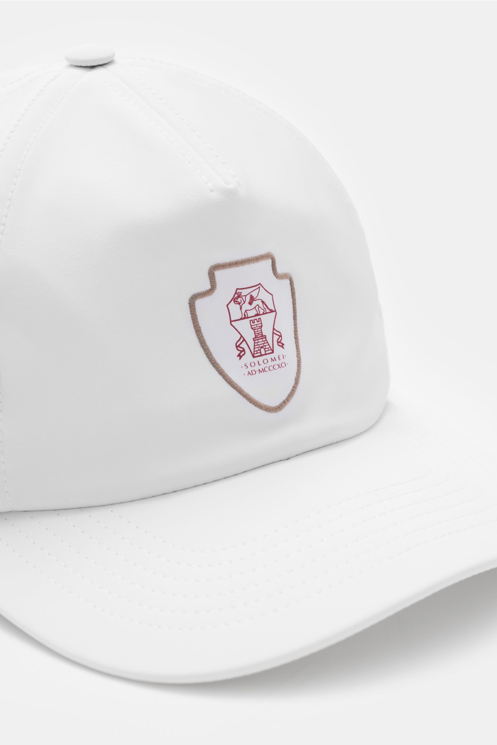 Brunello Cucinelli Baseball-Cap weiß shown from a front-side angle with Solomeo logo patch, perforations, smooth microfiber, wide brim, and adjustable closure. Inspiriert vom Tennissport: Diese Cap aus dem Hause BRUNELLO CUCINELLI setzt mit dem Solomeo-Lo