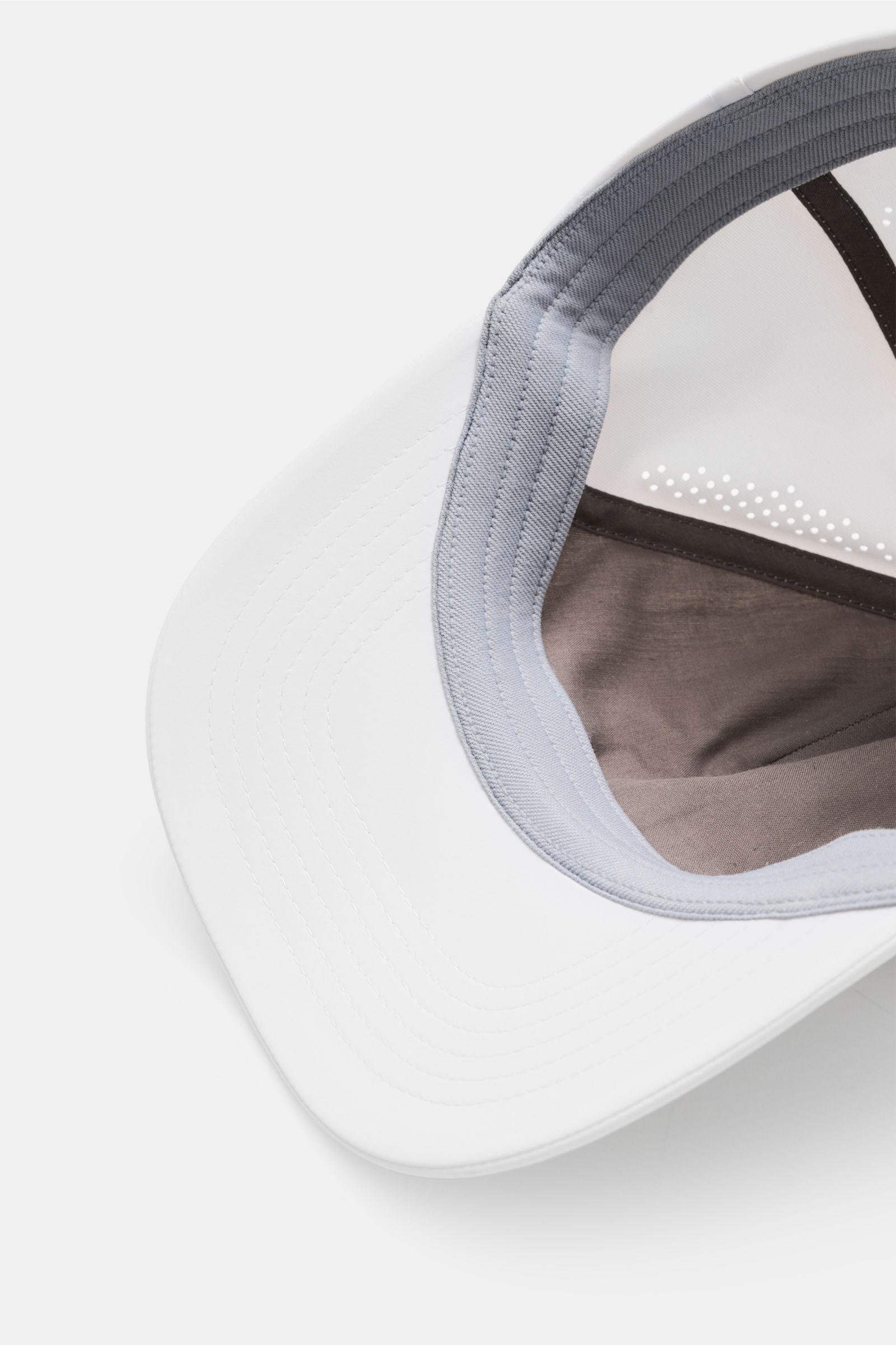 Inside view of the Brunello Cucinelli Baseball-Cap weiß showing grey inner band, ventilation perforations, and white brim, photographed from above.

Description: Inspiriert vom Tennissport: Diese Cap aus dem Hause BRUNELLO CUCINELLI setzt mit dem Solom