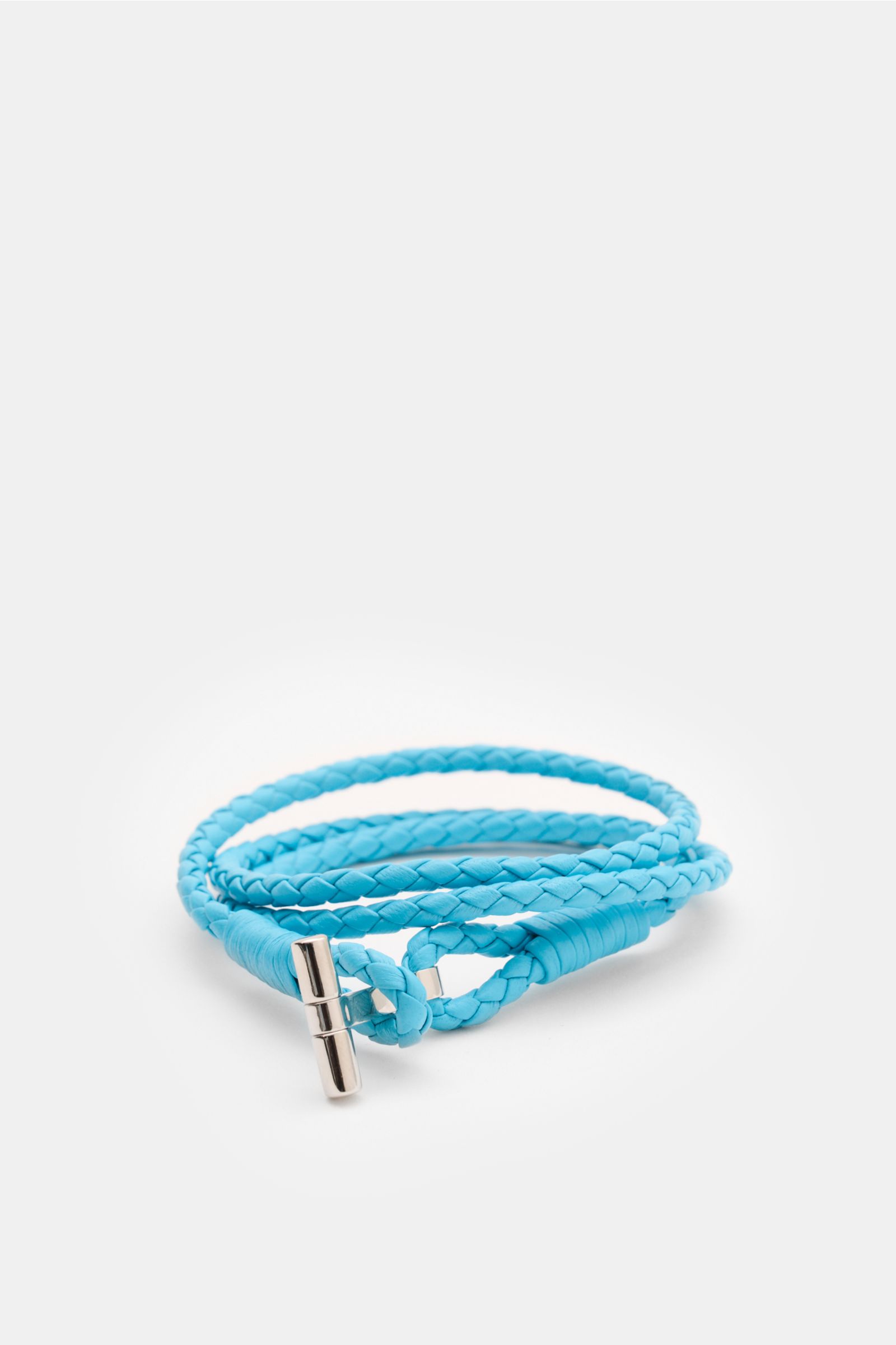 Close-up front perspective of Tom Ford Armband azurblau/silber, a slim braided light blue leather bracelet with silver T-bar loop closure.

Description: Wählen Sie mit dem schmalen Lederarmband aus geflochtenem Leder und mit goldfarbenem T-Verschluss v