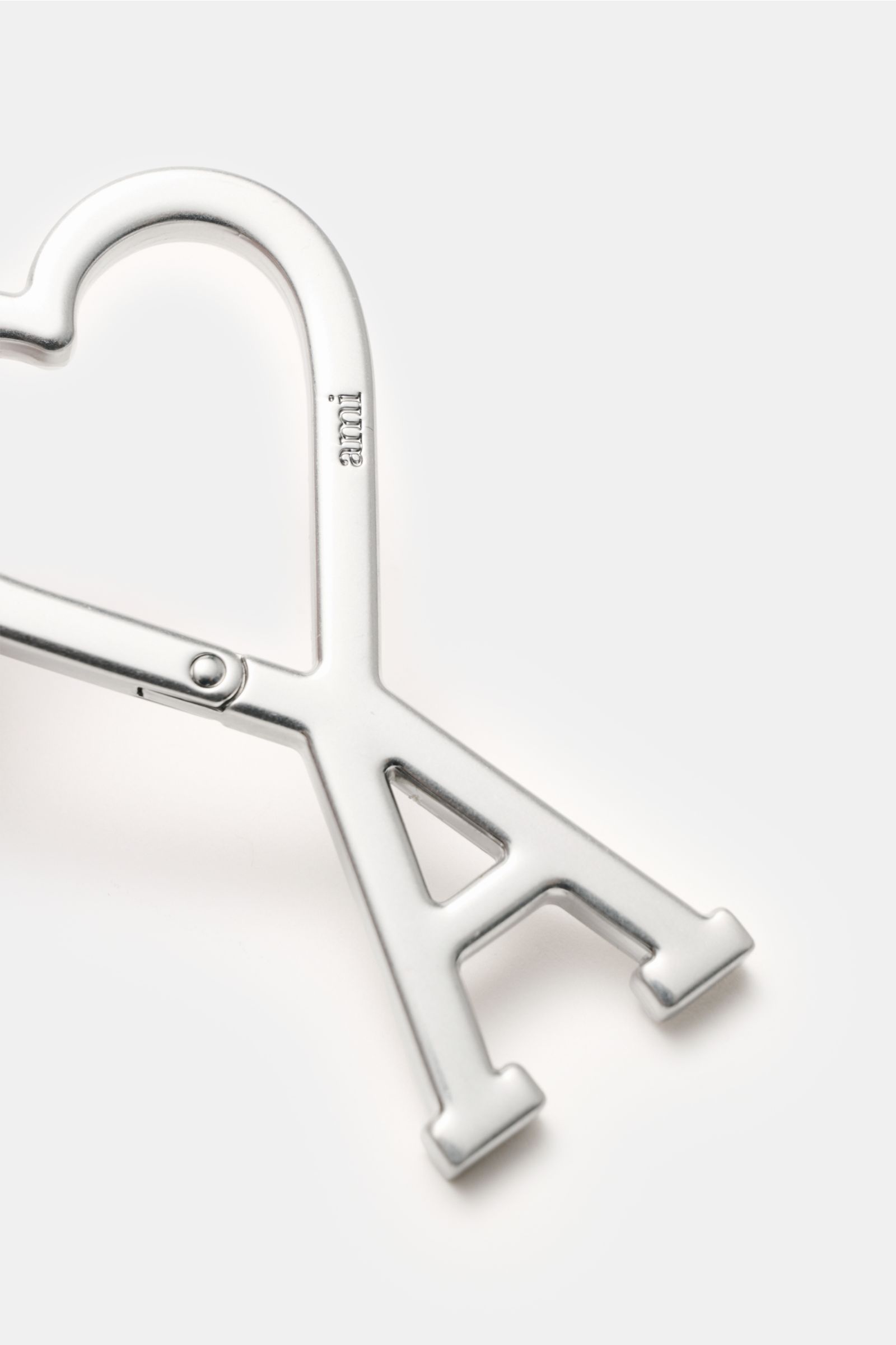 Ami Paris Schlüsselanhänger silber, Nahaufnahme aus schräger Perspektive, Unisex Accessoire mit AMI-Logo-Karabiner in Herzform, ca. 8x5 cm.