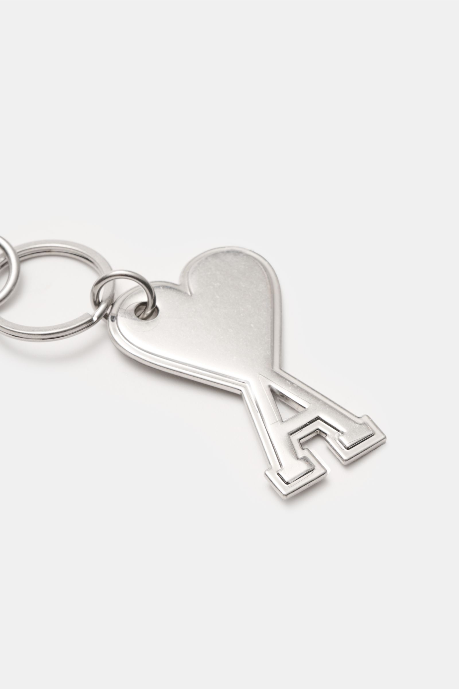Close-up of Ami Paris Schlüsselanhänger silber keychain with heart-shaped 'A' logo charm and practical carabiner, photographed from above.

Description: Unisex Accessoire von AMI PARIS: Dieser praktische Begleiter mit dem markentypischen 'A' mit Herz h