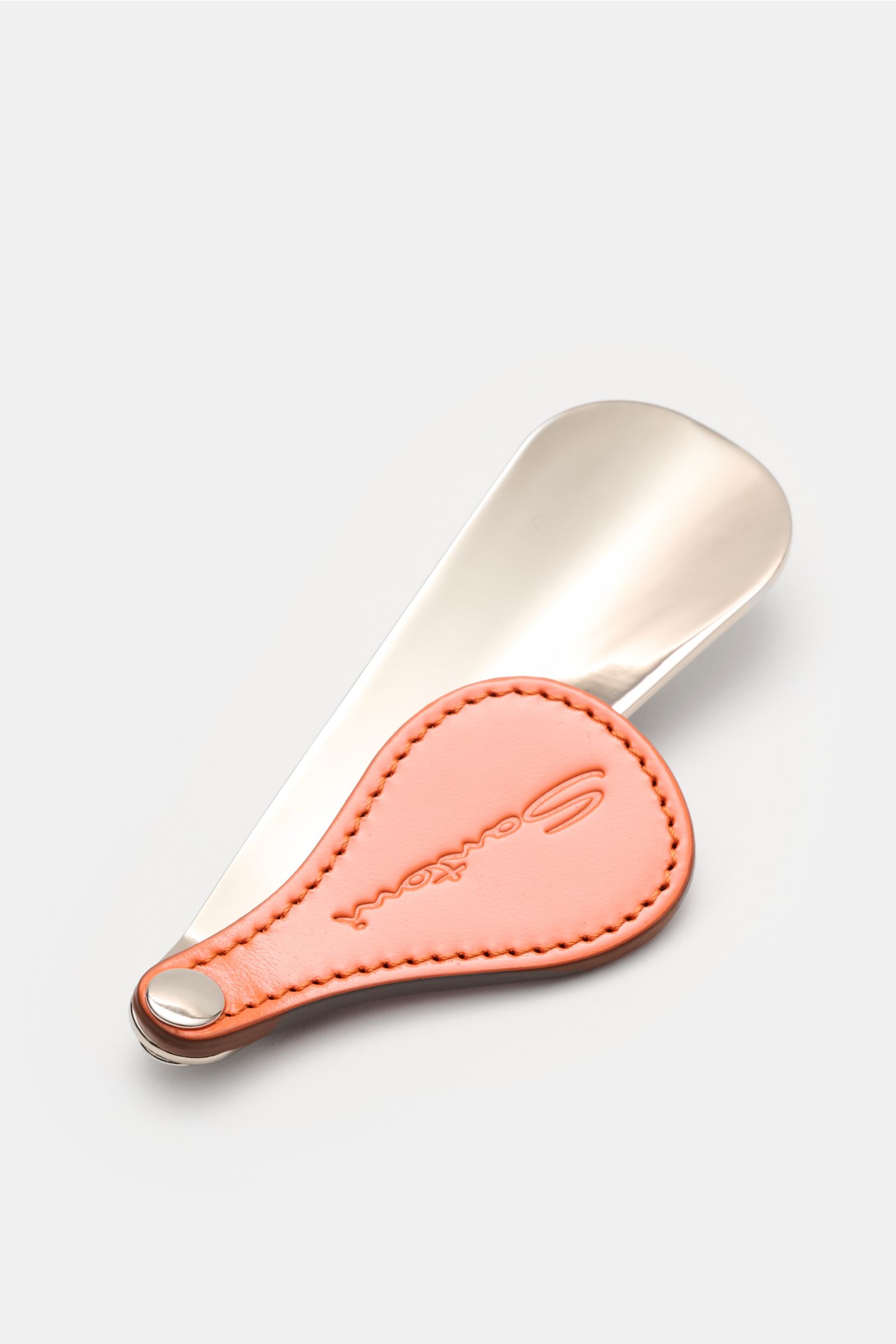 Top-down view of the Santoni Schuhlöffel silber shoehorn with a shiny metal spoon and a flexible orange leather handle embossed with SANTONI.

Der praktische Schuhlöffel mit Ledergriff von SANTONI erfüllt mit seiner handlichen Größe auch auf Reisen sei