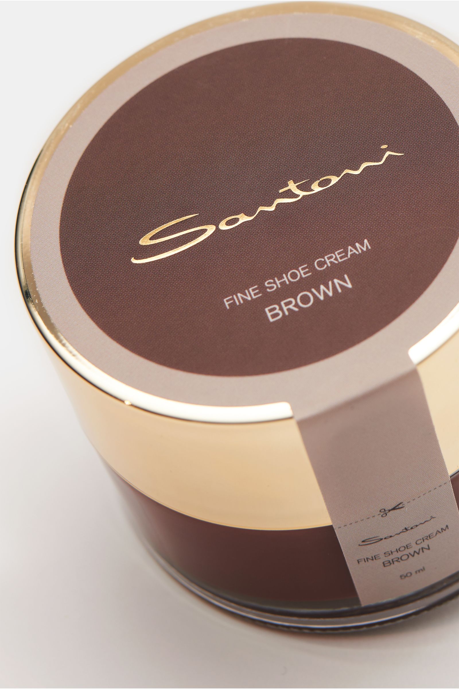 Close-up, top-down angled view of Santoni Schuhcreme braun 50 ml, a brown shoe cream tin with gold lid, essential for hand-crafted Santoni shoes, featuring high wax content, smooth leather care, color and shine refresh, made in Italy.