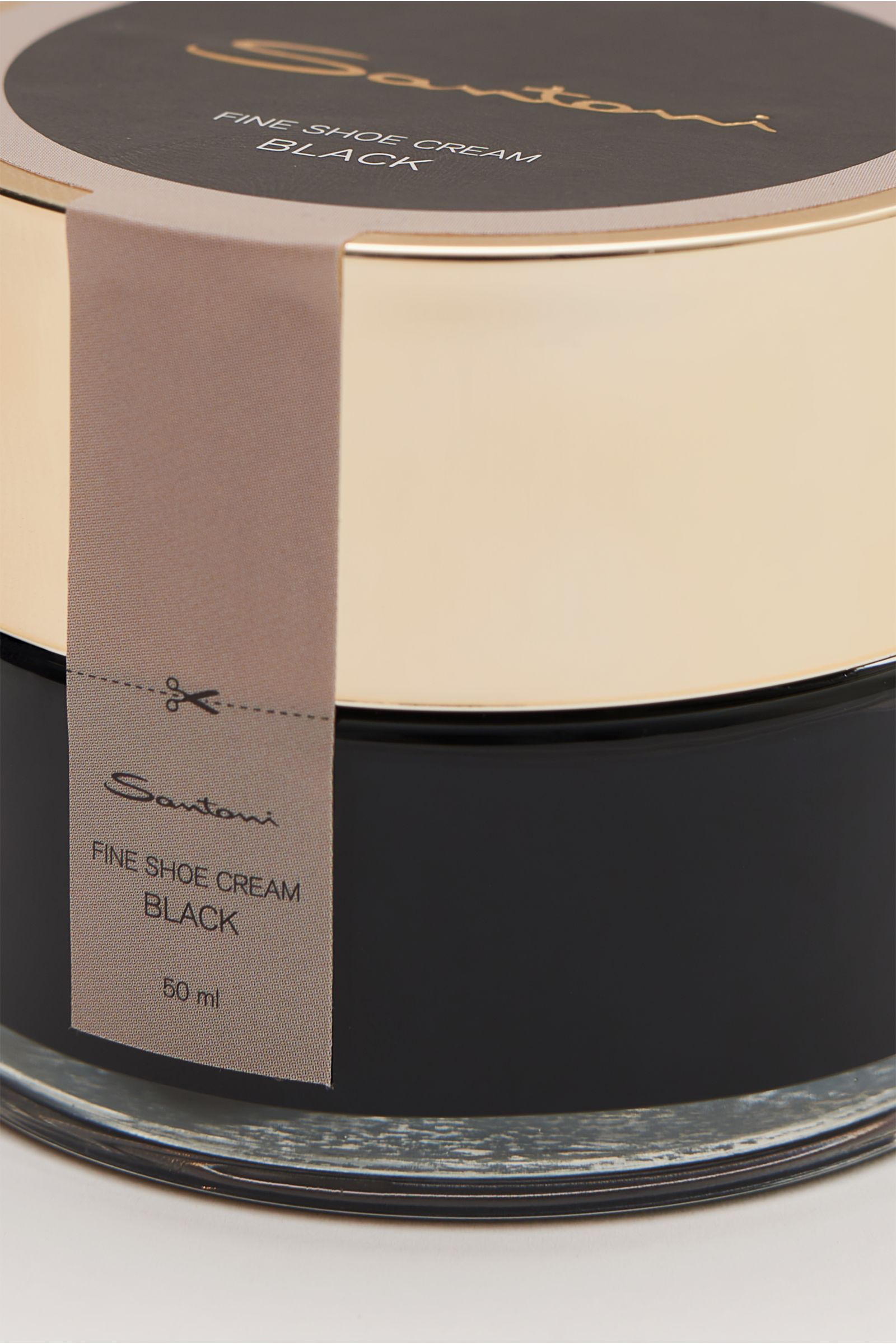 Close-up angled view of Santoni Schuhcreme schwarz 50 ml in a black glass jar with a gold lid and beige label, perfect for smooth leather care.

Description: Unverzichtbares Utensil für die handgearbeiteten Meisterwerke von SANTONI: Perfekt auf den Sch