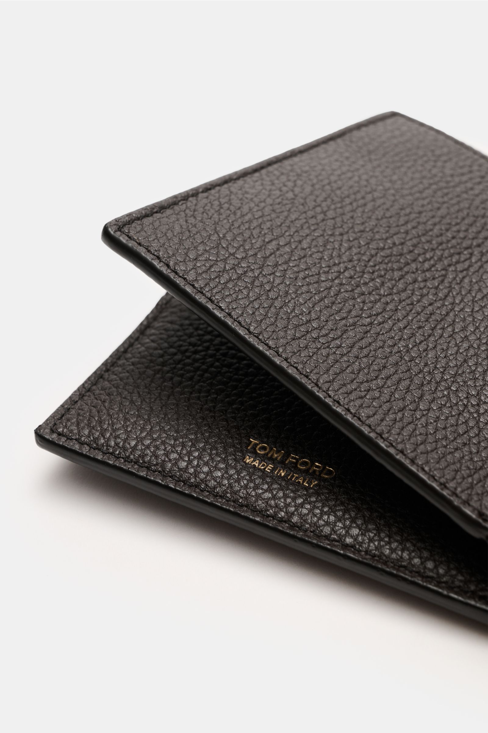 Tom Ford Portemonnaie dunkelbraun aus edlem, markant genarbtem Kalbleder mit goldfarbener Logo-Prägung seitlich fotografiert.
