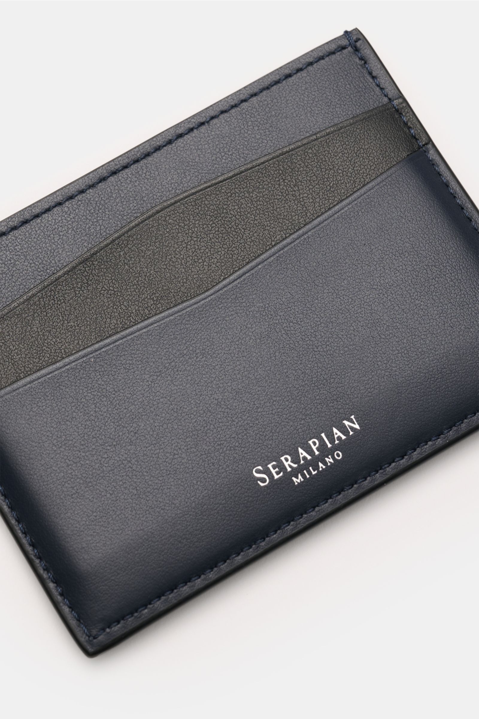 Close-up front view of Serapian Kartenetui 'Mosaico' navy/schwarz cardholder in smooth navy and black leather with silver logo.

Wertvoller Begleiter: Das handgearbeitete, für SERAPIAN ikonische 'Mosaico'-Flechtwerk verleiht diesem Kartenetui luxuriöse
