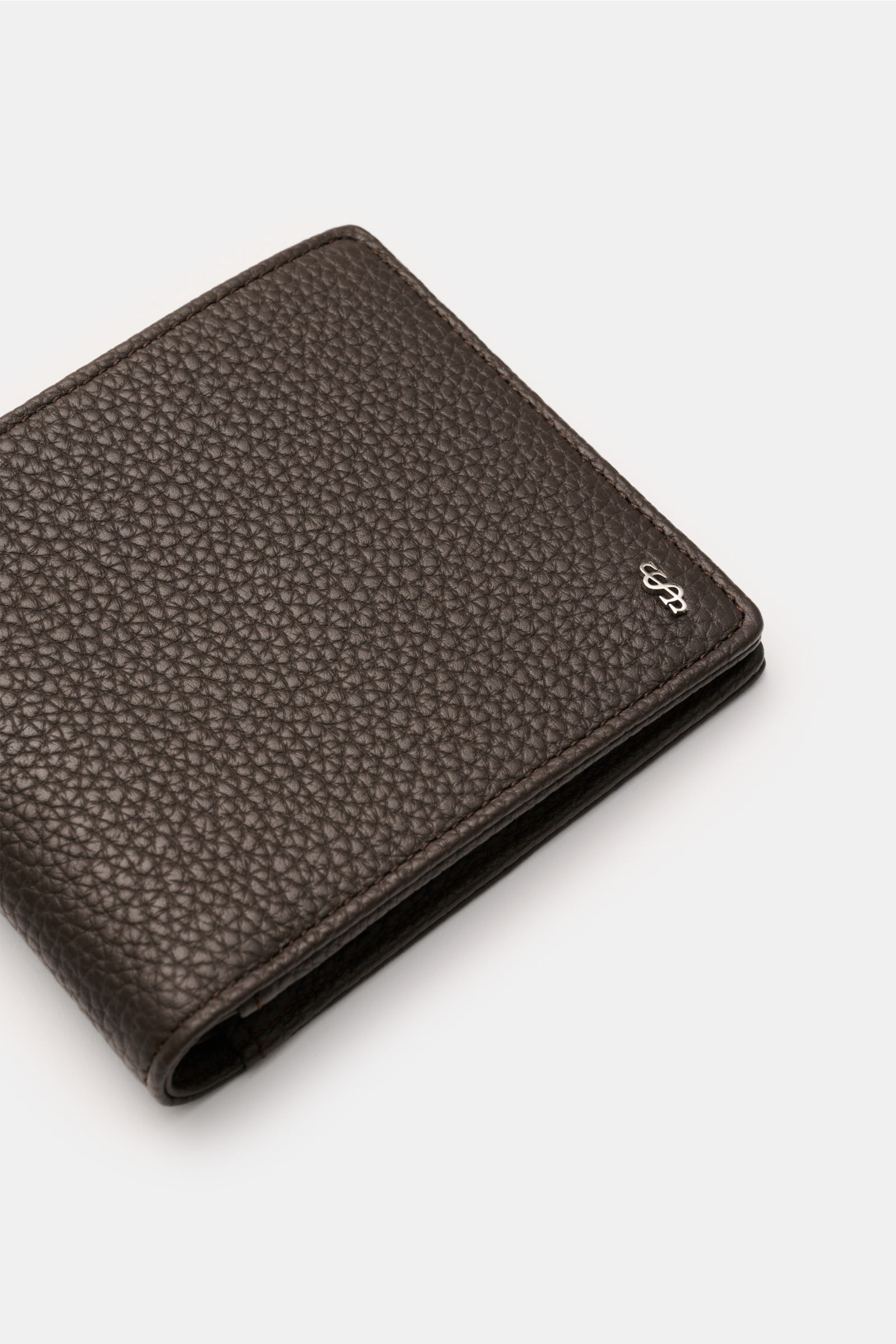 Close-up angled view of Serapian Portemonnaie dunkelbraun in dark brown cashmere leather with silver logo, showing textured grain.

Alles Wesentliche stilvoll organisiert: Das klassische Portemonnaie von SERAPIAN aus edlem Cashmere-Leder bietet sichere
