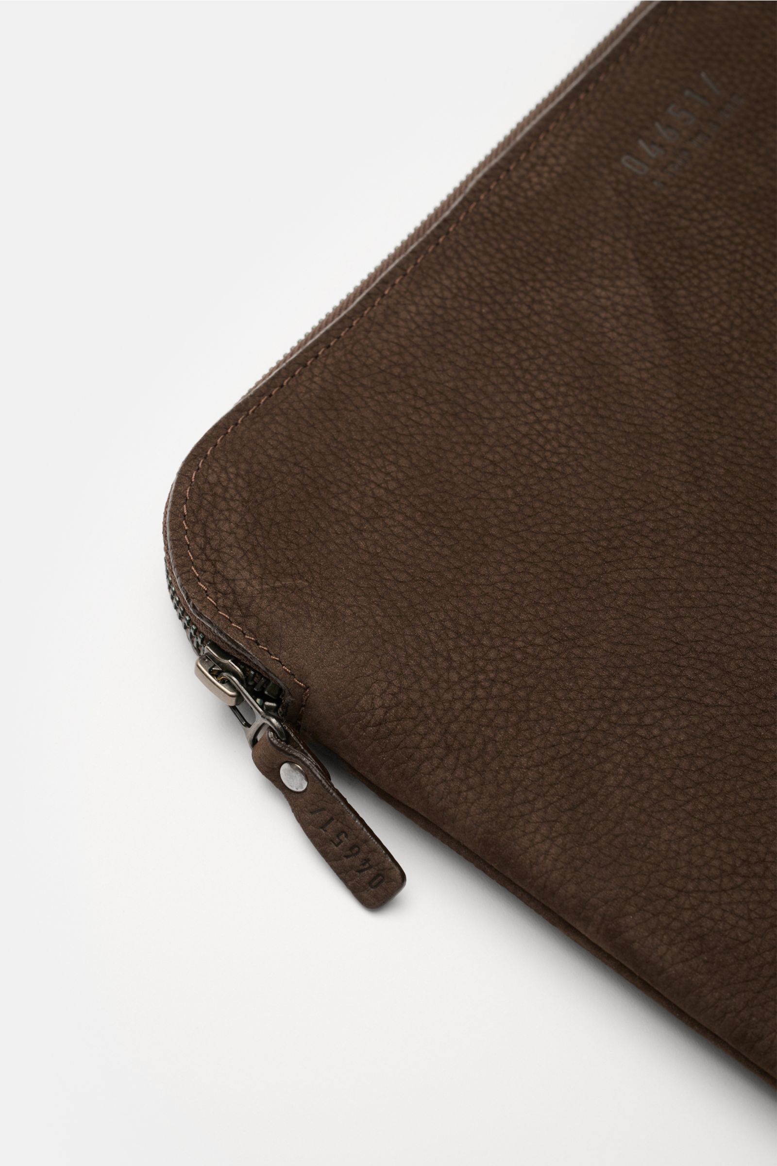 04651/ A trip in a bag Laptop Sleeve dunkelbraun aus Nubukleder, seitliche Nahaufnahme mit Reißverschluss und geprägtem Logo, weich gefüttert