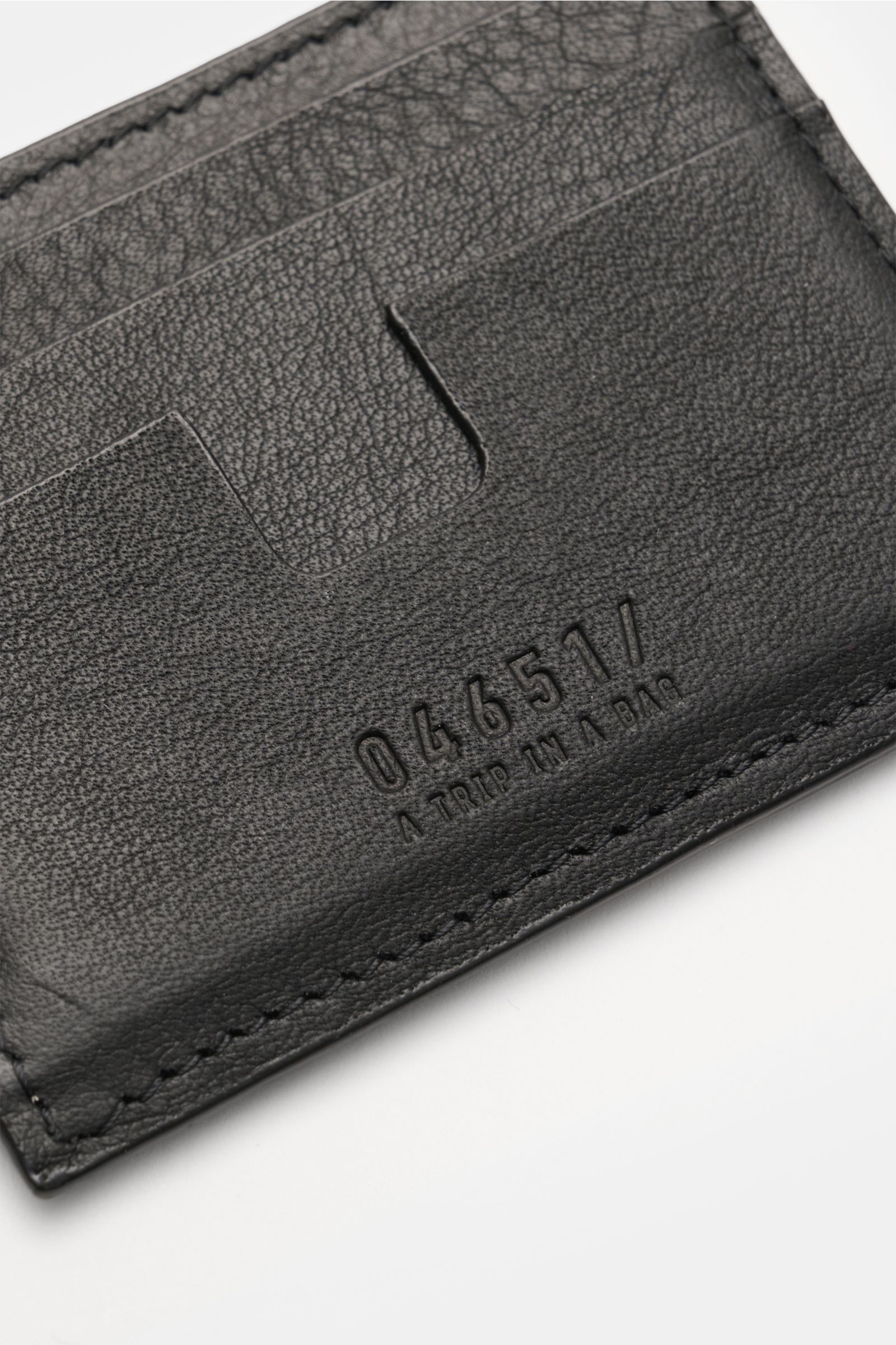 Close-up view of the black 04651/ A trip in a bag Kartenetui schwarz made of luxurious nubuck leather, showing six card slots, a main compartment, and the embossed 04651/ logo; minimalist everyday essential measuring approx. 10 x 8 cm, ideal for travel or