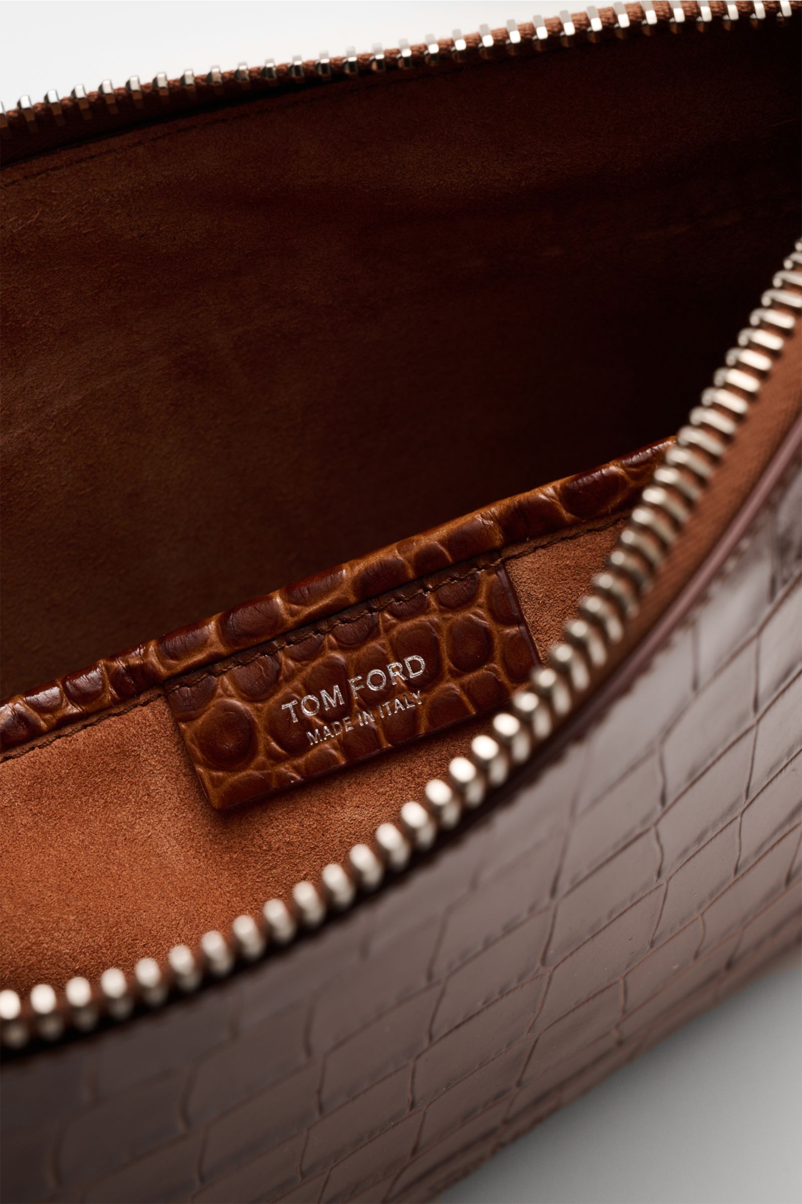 Close-up inside view of Tom Ford Tasche braun in reptile-look calf leather with silver zipper, logo embossing, and suede interior.

Praktischer Begleiter im Alltag: Hochwertiges Kalbleder im Reptilien-Look und dezente Logo-Prägung machen diese elegante