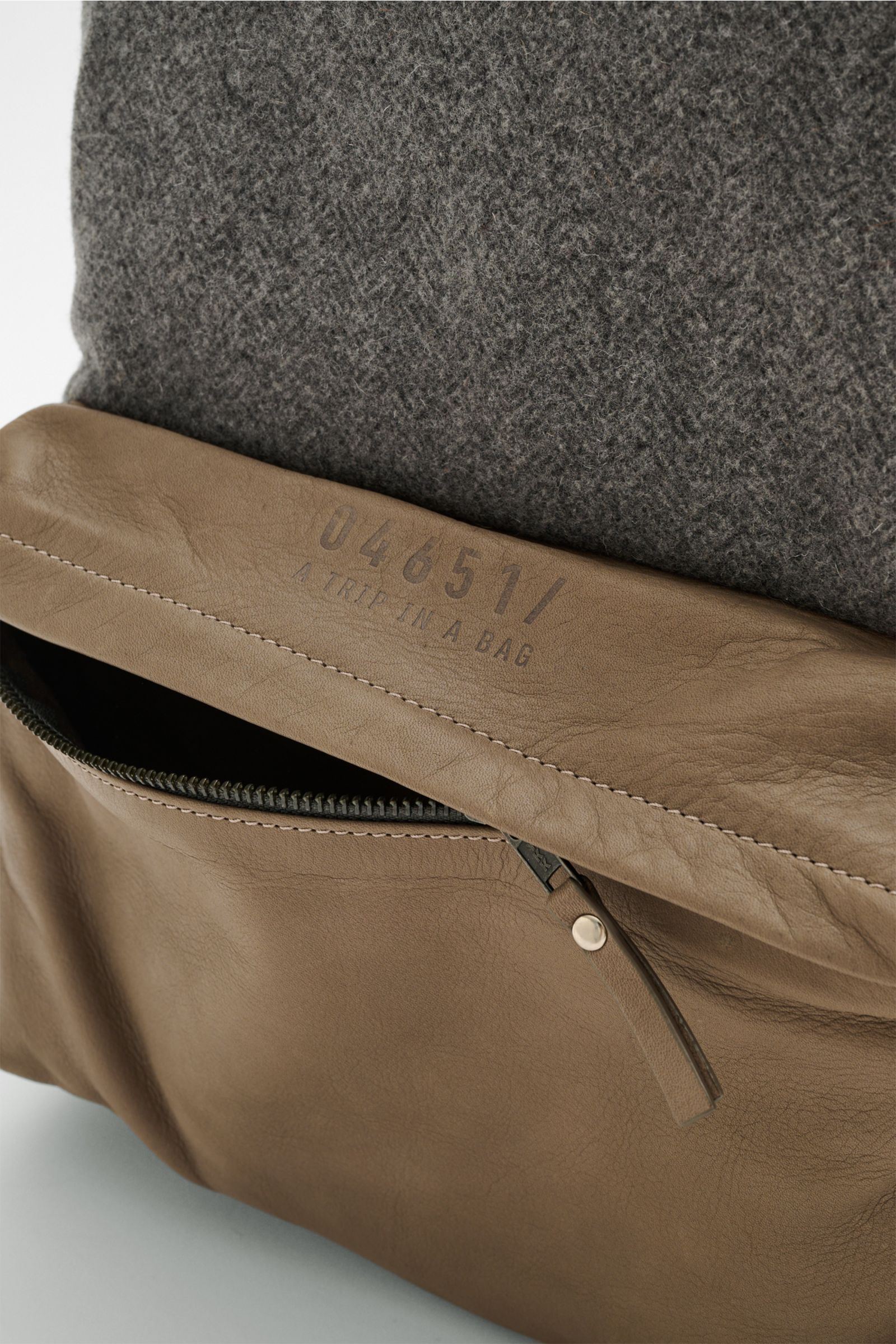 Nahaufnahme des 04651/ A trip in a bag Rucksack 'Herringbone' grau meliert/taupe mit geöffneter Lederaußentasche und Fischgrat-Textil von oben fotografiert.