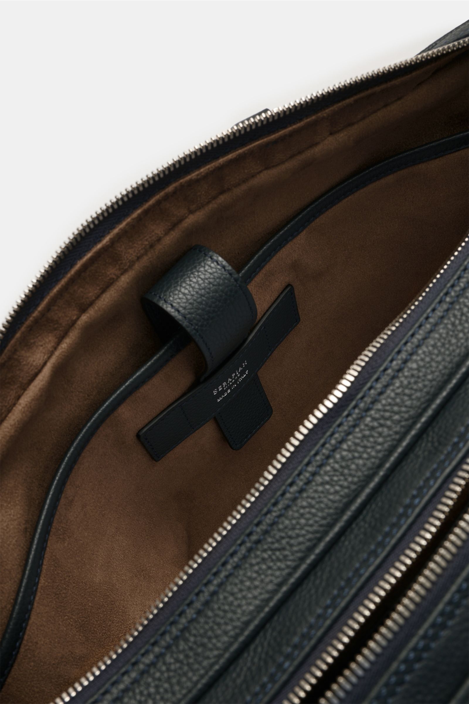 Close-up top-down view inside the Serapian Aktentasche dark navy, showing brown textile lining, padded laptop compartment, and silver zipper in markant genarbtes Kalbleder. Edle Lederqualität und erstklassiges Handwerk vereinen sich in dieser Aktentasche 