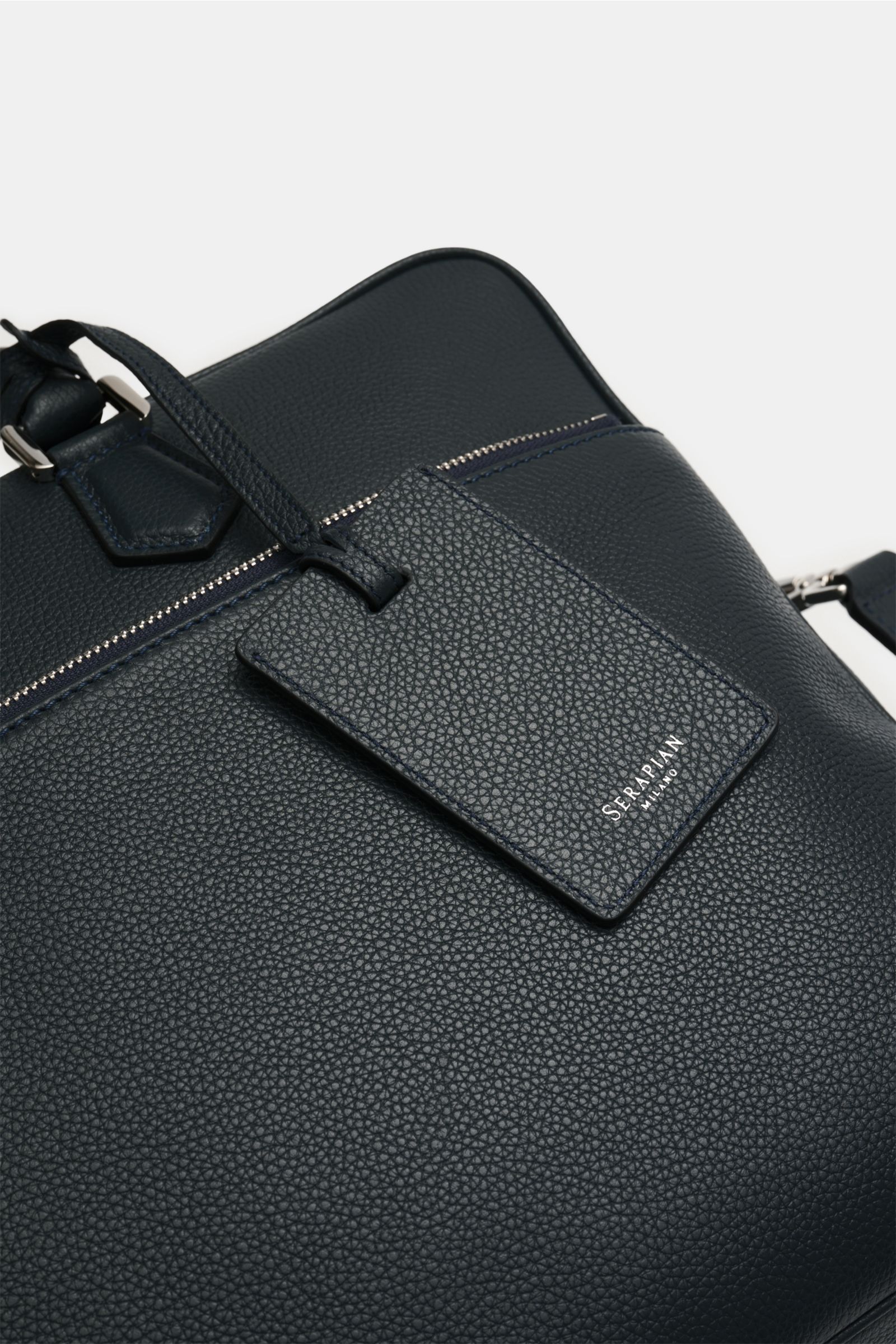 Close-up top-front view of Serapian Aktentasche dark navy in markant genarbtes Kalbleder with silver hardware, robust handles, and logo tag.