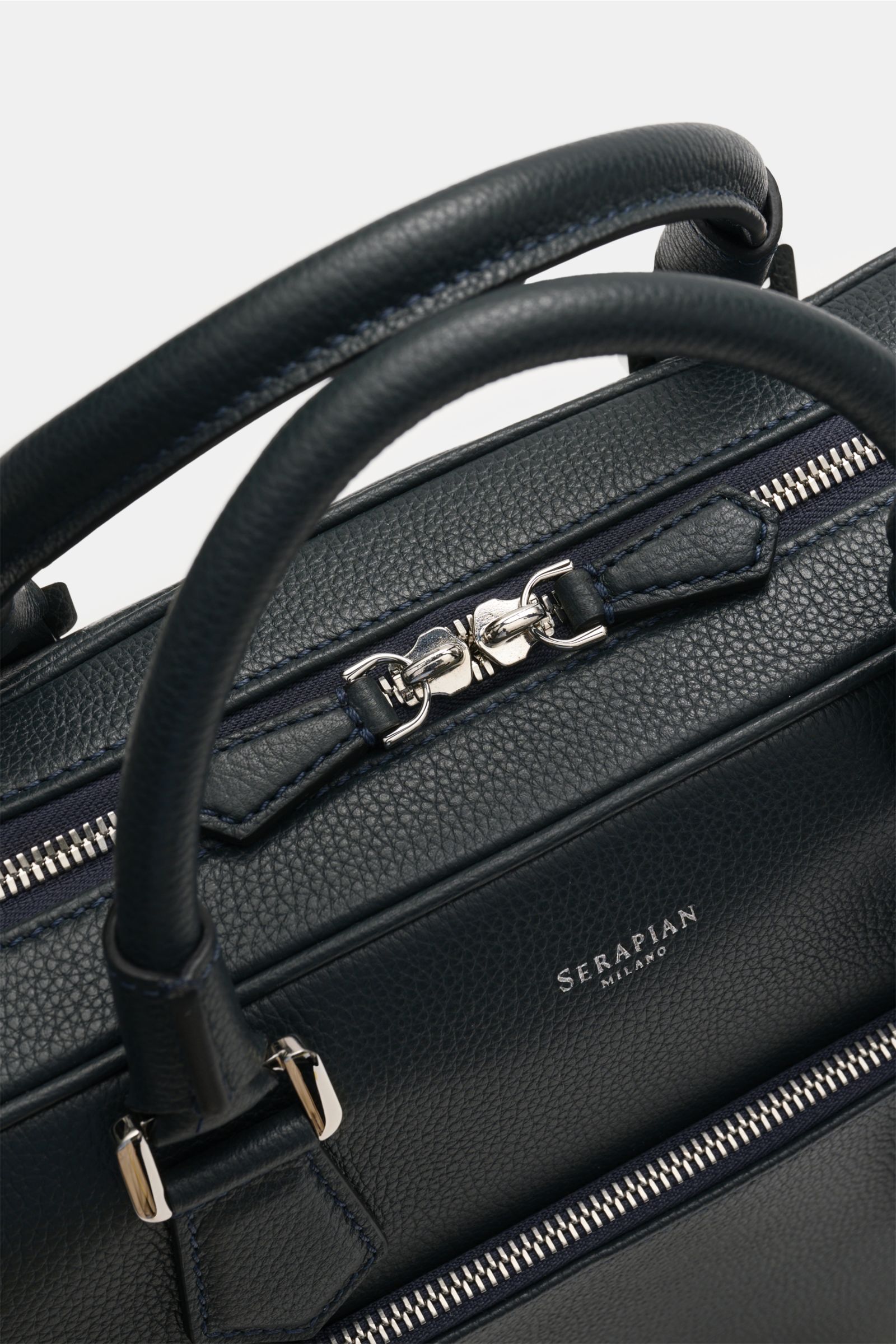 Serapian Aktentasche dark navy aus markant genarbtem Kalbleder, silberfarbene Hardware, Tragegriff und Reißverschluss, Nahaufnahme von oben.