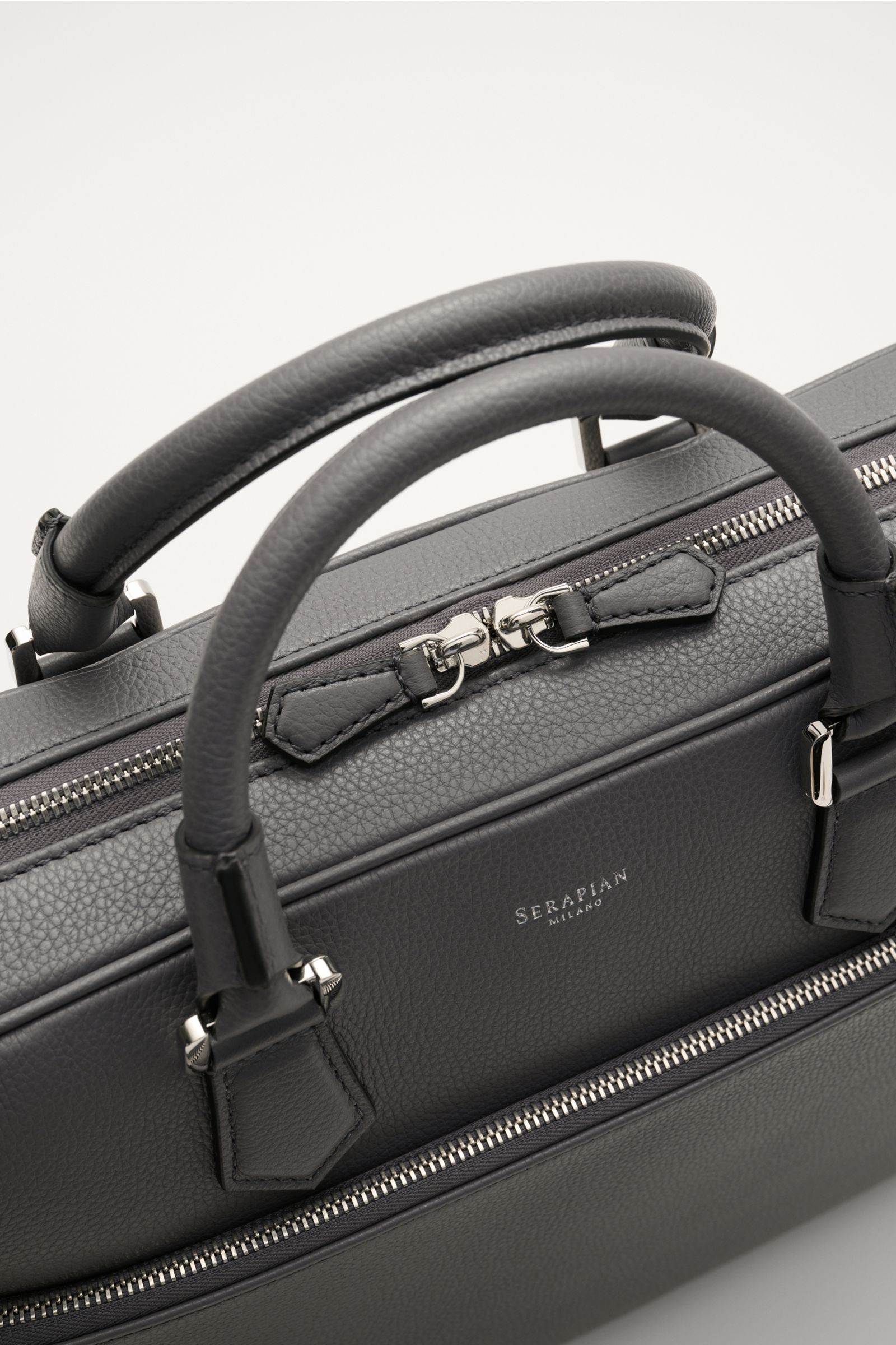 Close-up top view of Serapian Aktentasche grau in gray marked calf leather with silver hardware, robust handles, and dual zippers.
