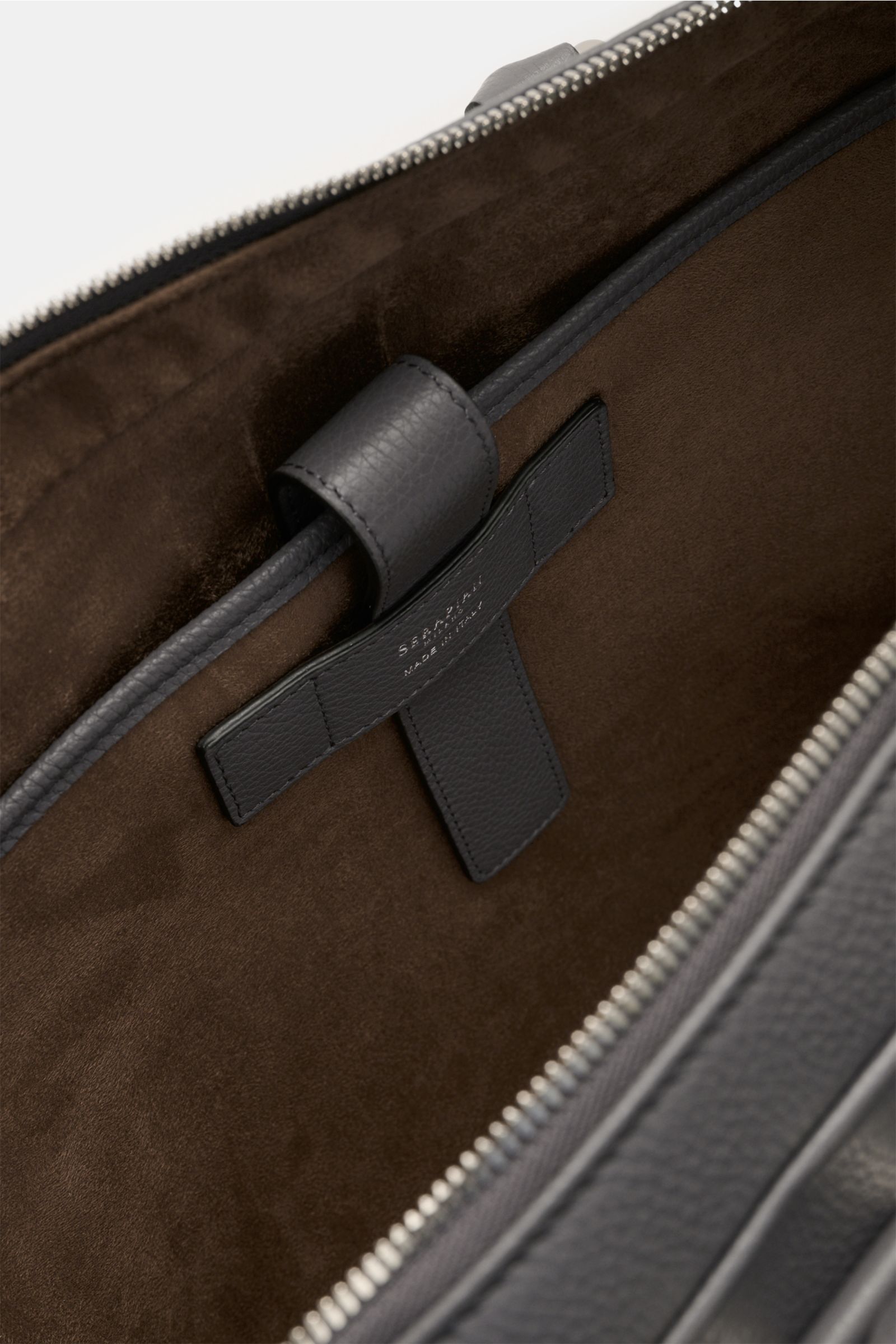 Close-up inside view of the Serapian Aktentasche grau showing soft brown textile lining, marked calf leather strap, and silver zipper.

Description: This image features a close-up perspective inside the Serapian Aktentasche grau, highlighting its luxuriou