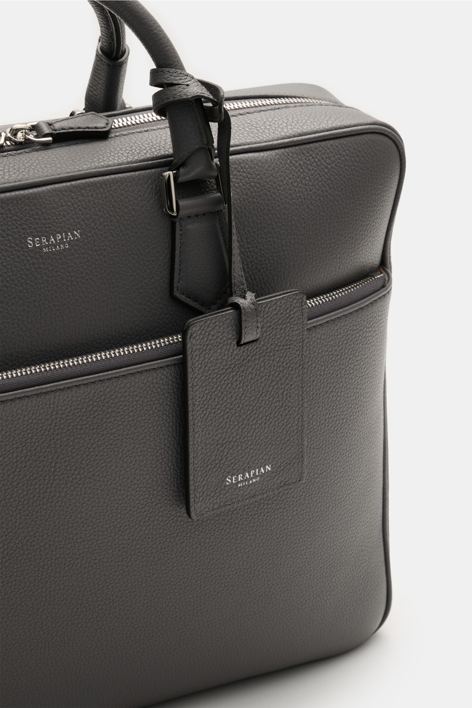 Close-up front-side view of the Serapian Aktentasche grau in markant genarbtes Kalbleder with silver hardware, robust handles, zipper pocket, and logo tag.