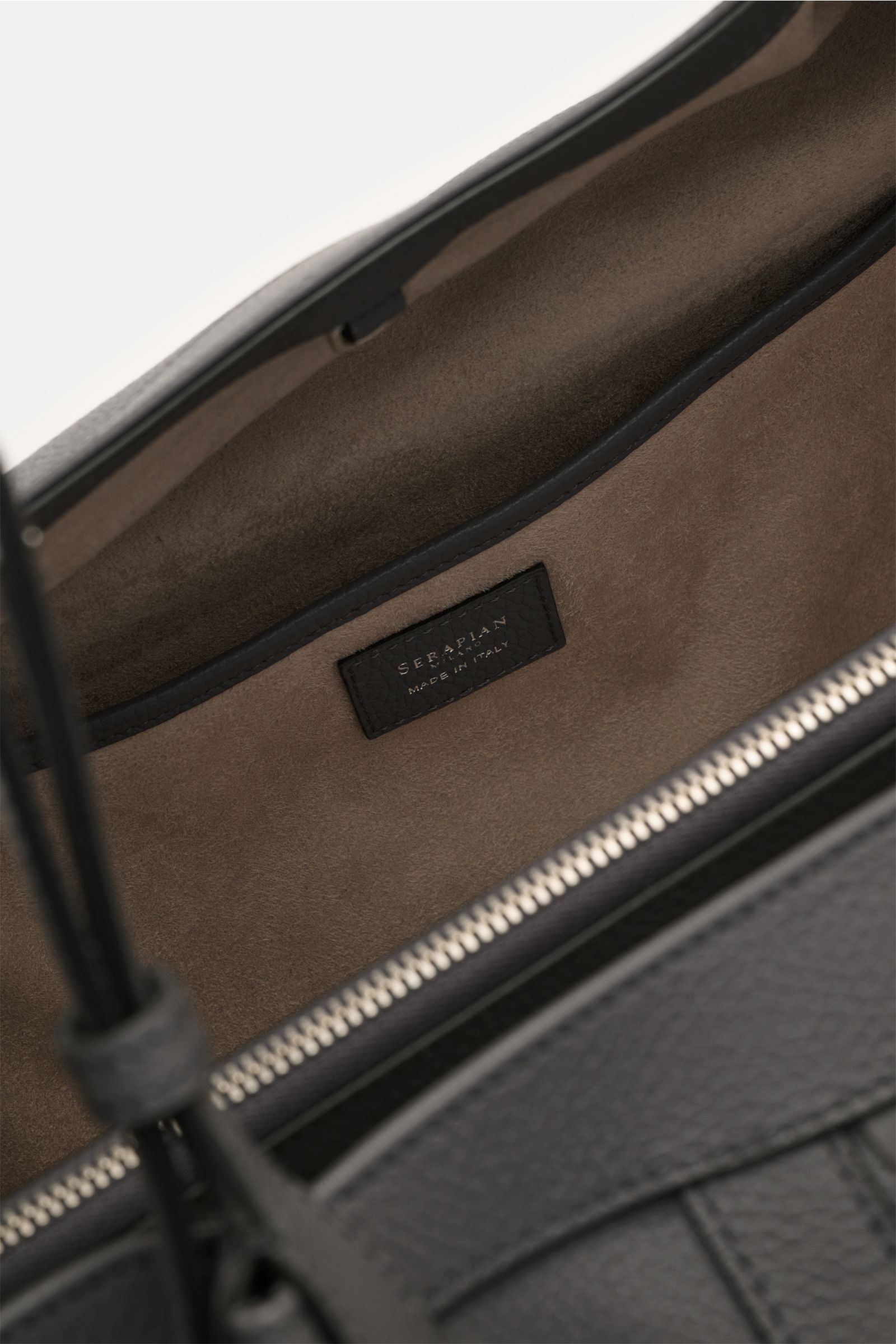 Close-up interior view of the Serapian Shopper grau showing soft suede lining, zippered compartment, and black leather label 'Serapian Made in Italy.' Für diesen luxuriösen Shopper verwendet SERAPIAN feinstes Cashmere-Leder und wurde aufwändig mit dem 'Mo
