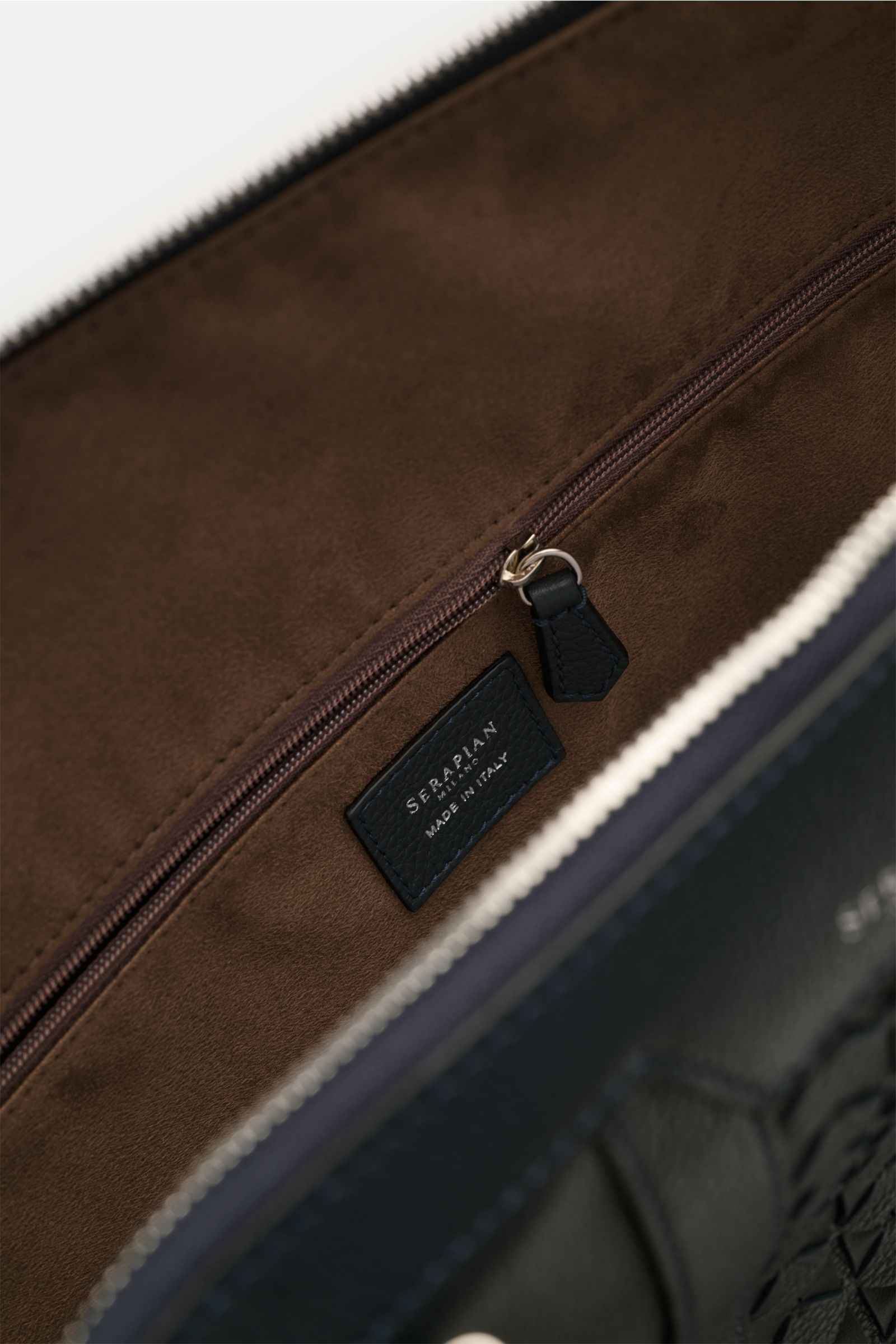 Serapian Weekender navy von innen fotografiert, zeigt braunes Innenfutter mit Reißverschlussfach und Leder-Logo, luxuriöses Cashmere-Leder.