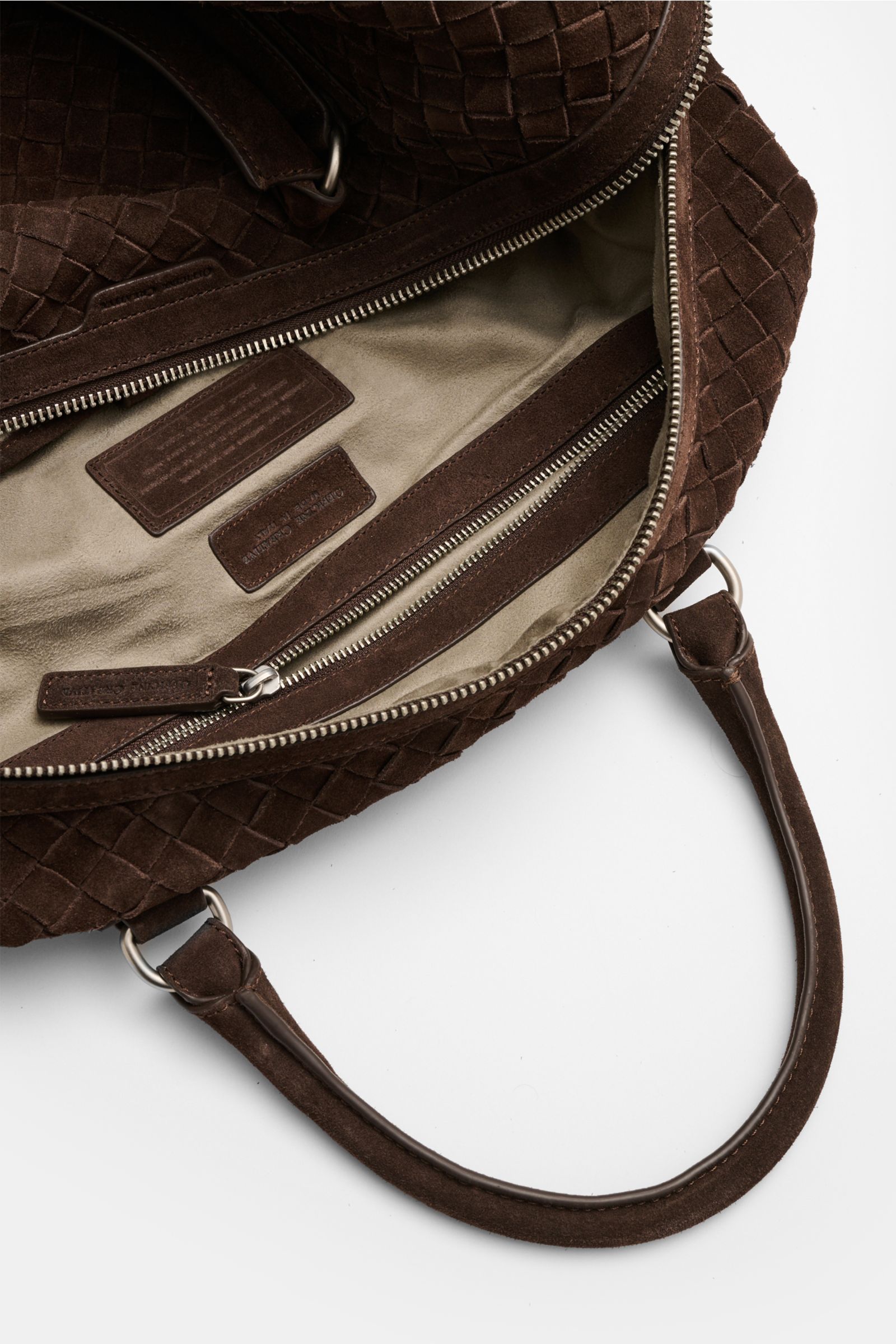 Officine Creative Weekender dunkelbraun aus handgewebtem Veloursleder, offene Perspektive auf Innenfach mit Zipper, robuster Tragegriff, seidenmatte silberne Hardware.