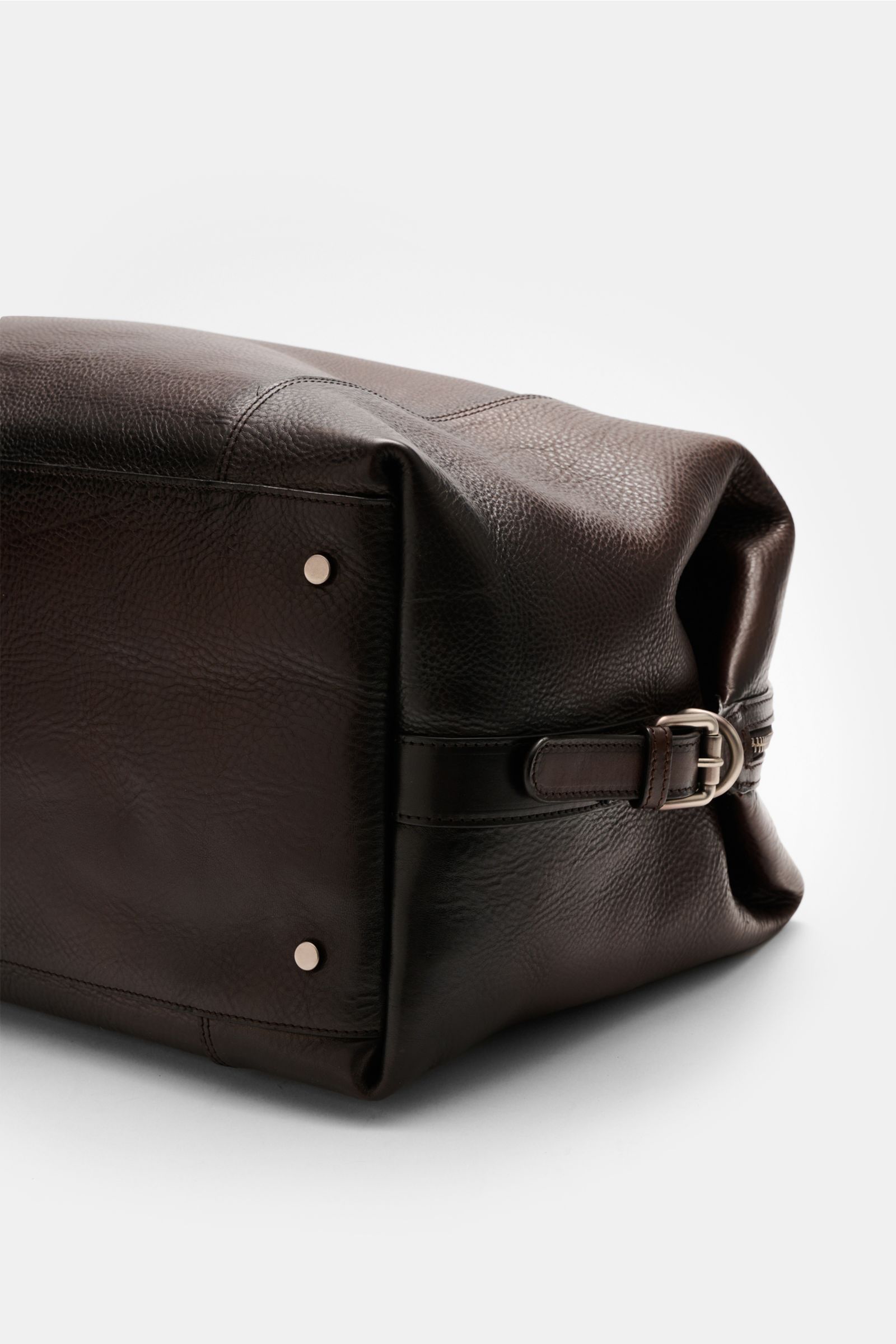 Officine Creative Weekender dunkelbraun aus fein genarbtem Leder mit matter Hardware, schräg liegend, robusten Tragegriffen und silberfarbener Schnalle.