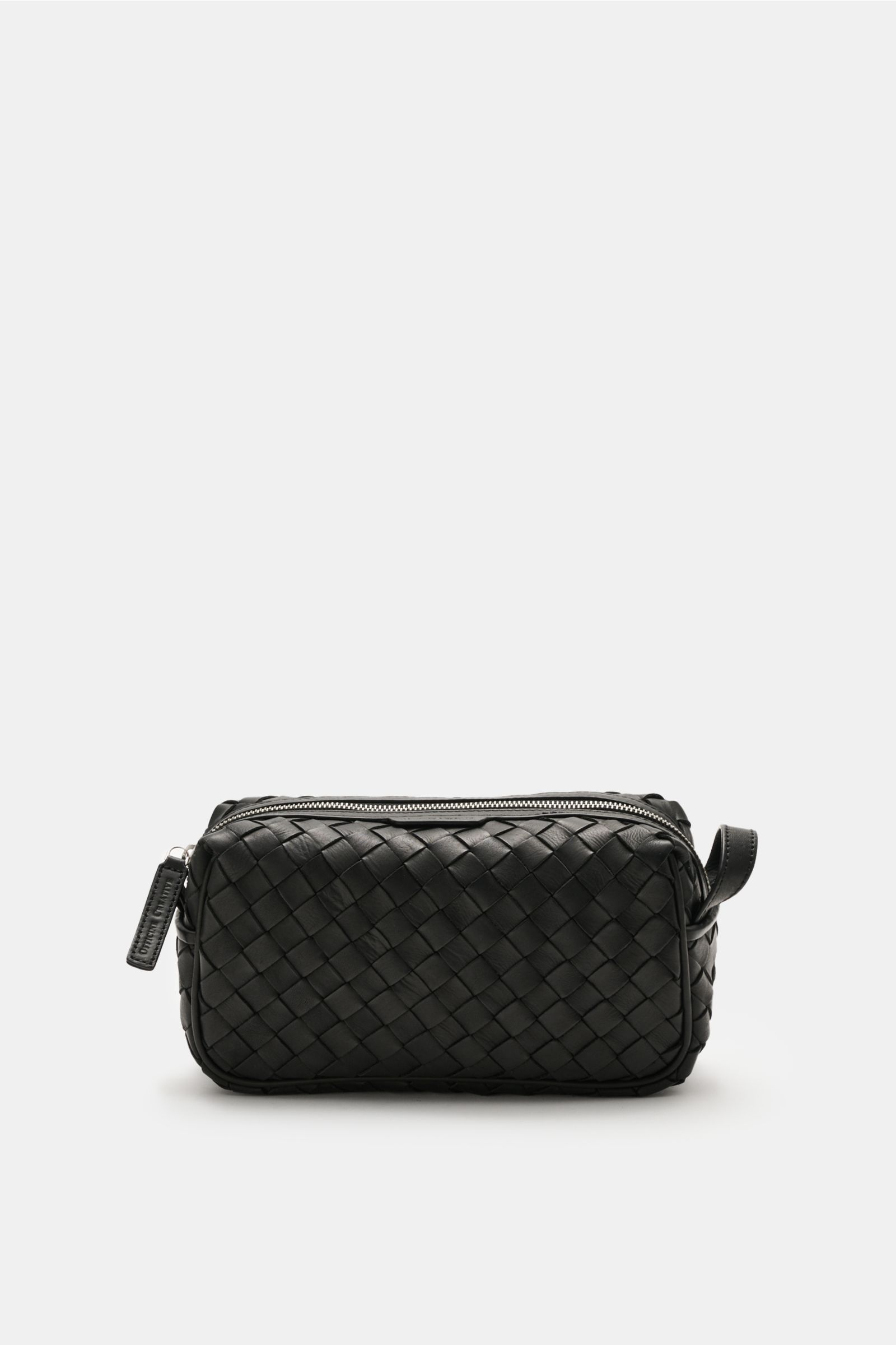 Officine Creative Necessaire schwarz, front view showing black woven leather exterior, silver zipper, practical wrist strap, and spacious main compartment, ideal travel essential. Praktisches Reise-Essential von OFFICINE CREATIVE: Dieses edle Necessaire ü