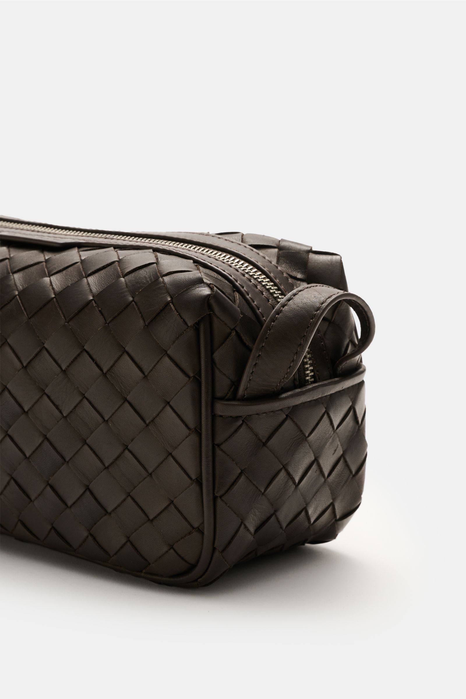 Officine Creative Necessaire dunkelbraun mit geflochtener Leder-Außenseite, silberfarbenem Reißverschluss, Handschlaufe, seitliche Perspektive.