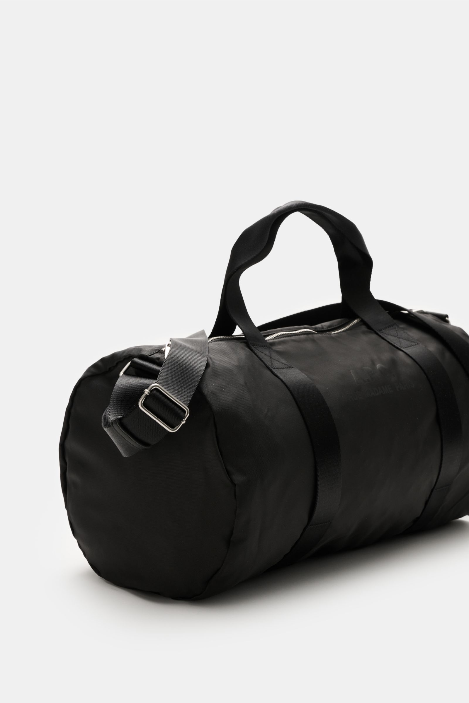 Side angle view of A.P.C. Tasche 'Gymbag Backstage' schwarz in black microfiber with silver hardware, durable straps, logo print, and spacious main compartment.