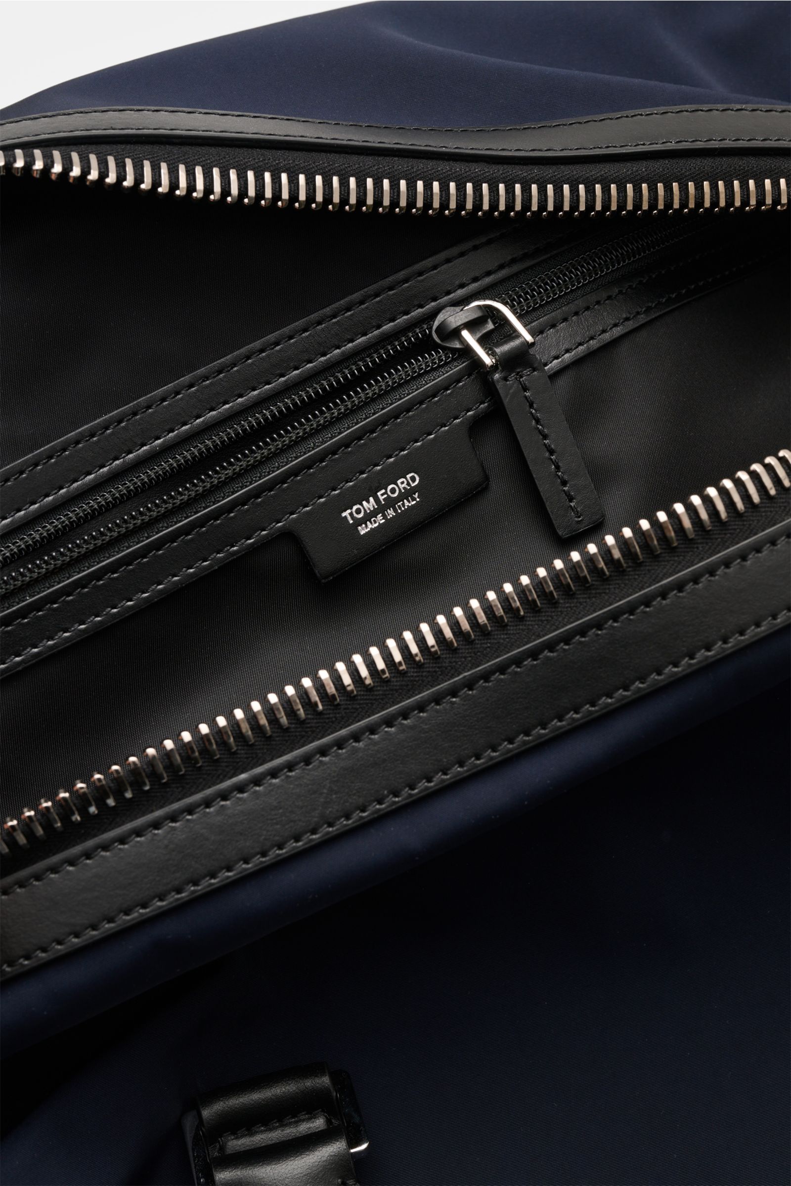 Alt tag (max 125 characters):
Close-up inside view of Tom Ford Weekender navy/schwarz showing black leather trim, silver zipper, and logo tag.

Description incorporating provided content:
Mit diesem Weekender aus robuster Microfaser und edlem Kalbleder