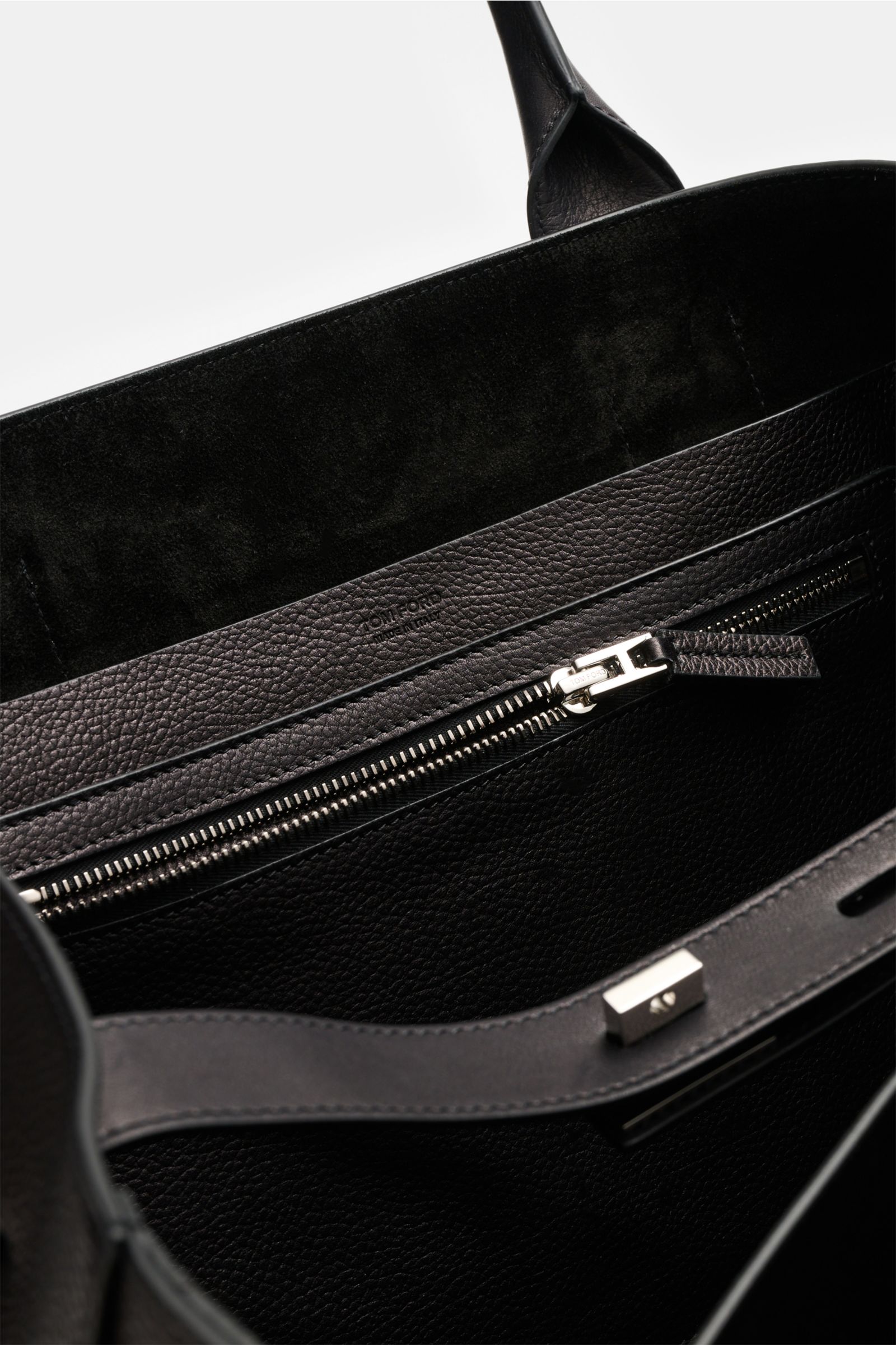 Interior close-up of Tom Ford Shopper schwarz showing finely grained calf leather, silver zipper, and suede lining from a top-down perspective.