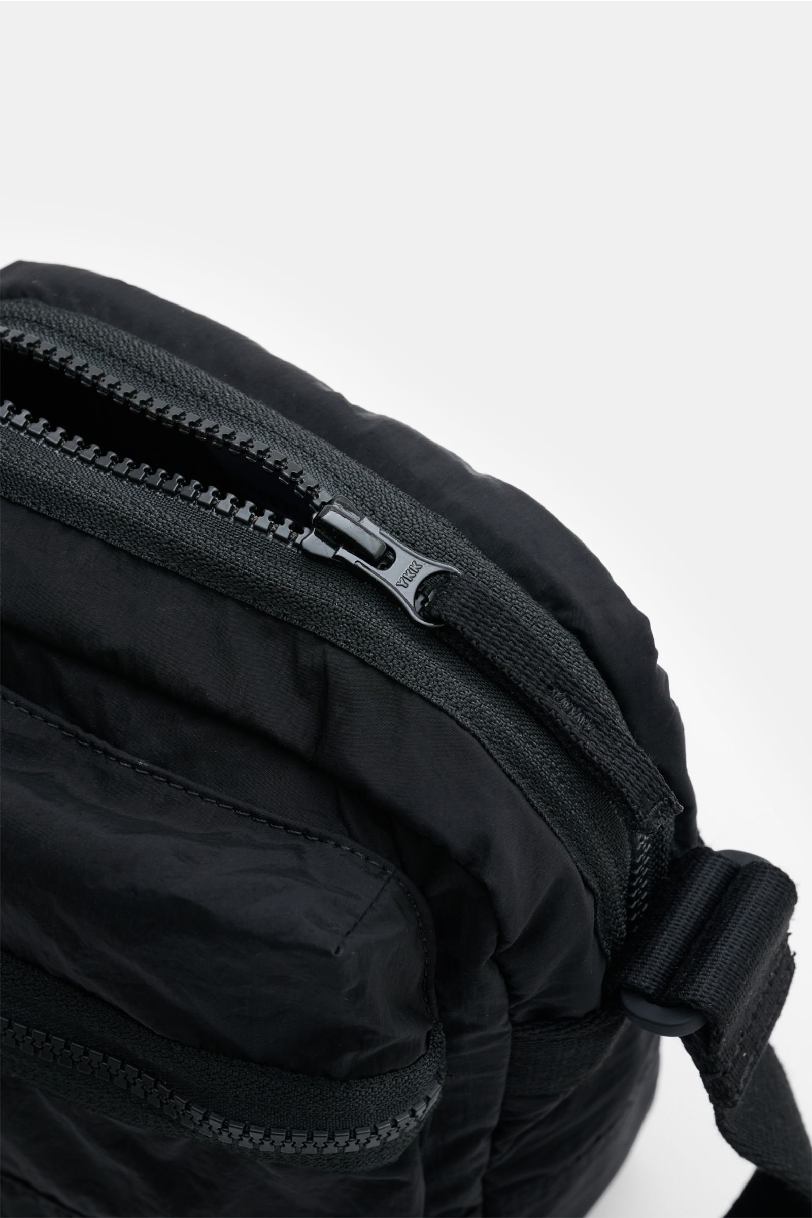 Close-up top-side view of the Stone Island Crossbody Bag 'Marsupio Tracolla' schwarz in black, showing the zipper and adjustable strap. Praktisch und stylish zugleich: Die Crossbody Bag 'Marsupio Tracolla' von STONE ISLAND überzeugt mit mehreren Fächern u