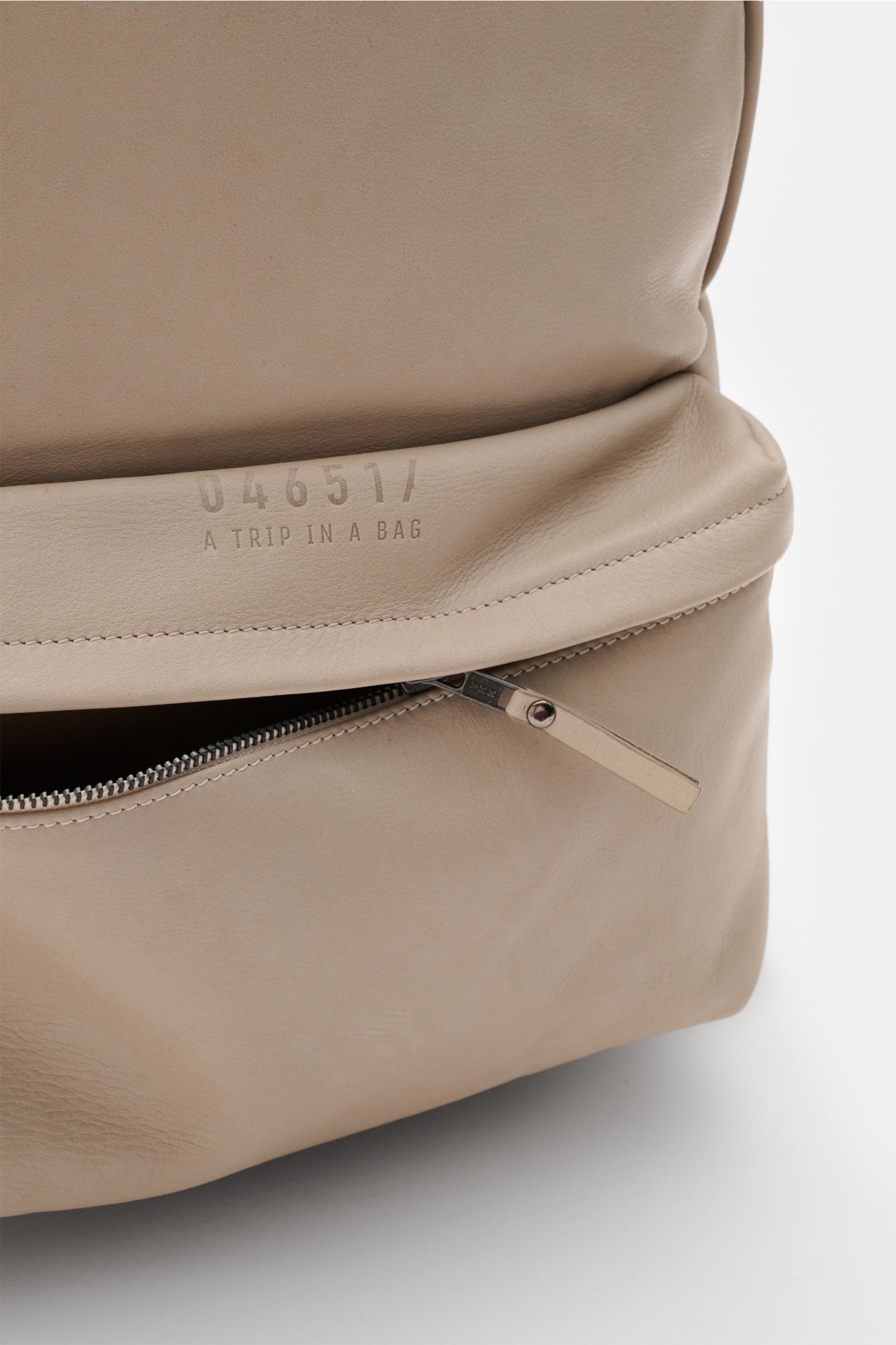 Close-up side view of beige Nubuk leather 04651/ A trip in a bag Rucksack 'Oyster Back Pack' navy showing zipper pocket and logo.