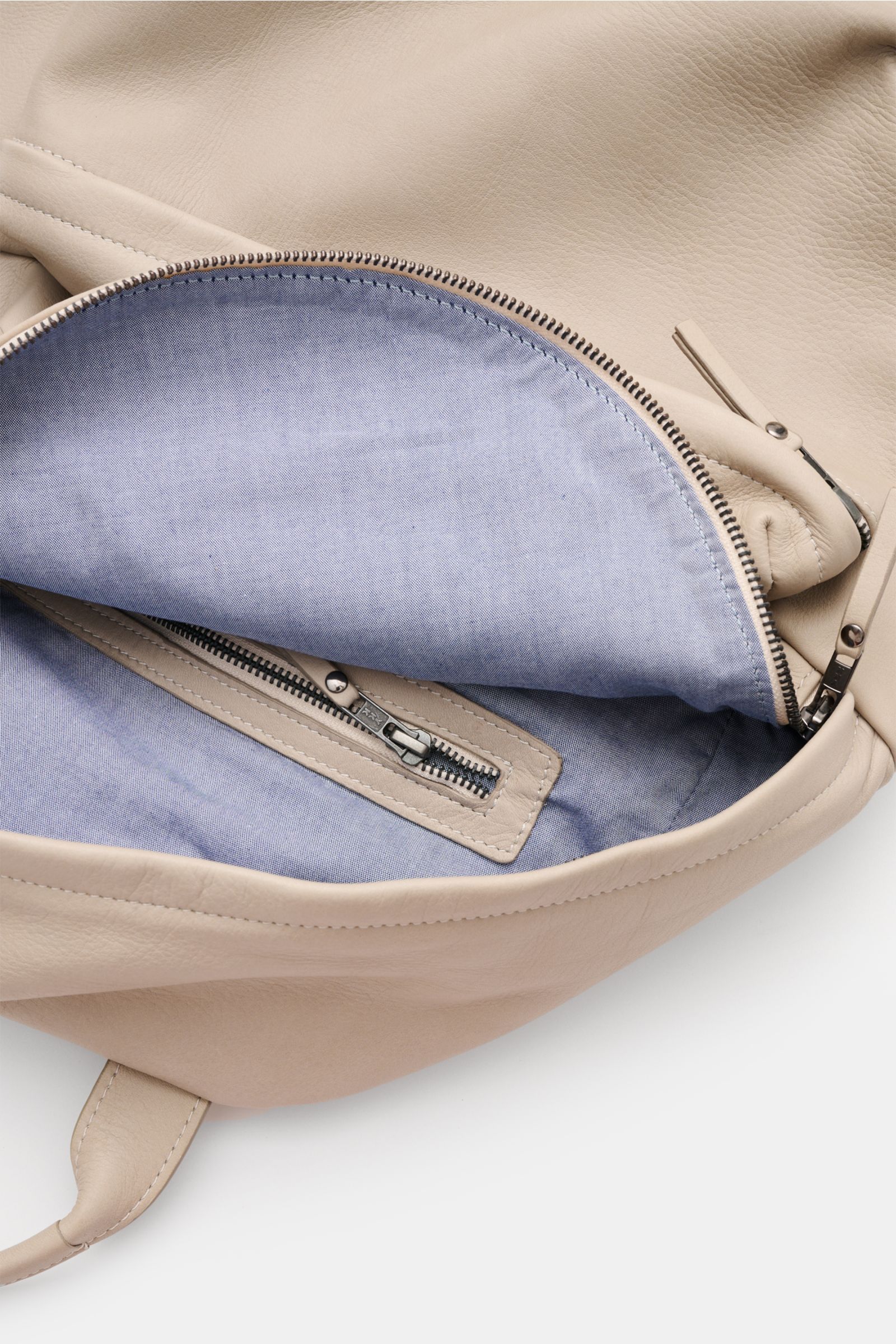 Close-up top-down view of the open 04651/ A trip in a bag Rucksack 'Oyster Back Pack' navy showing soft, textured nubuck leather exterior and smooth blue fabric lining with zipper pocket inside. 

Unkompliziert und stilvoll transportieren Sie Ihre Habs