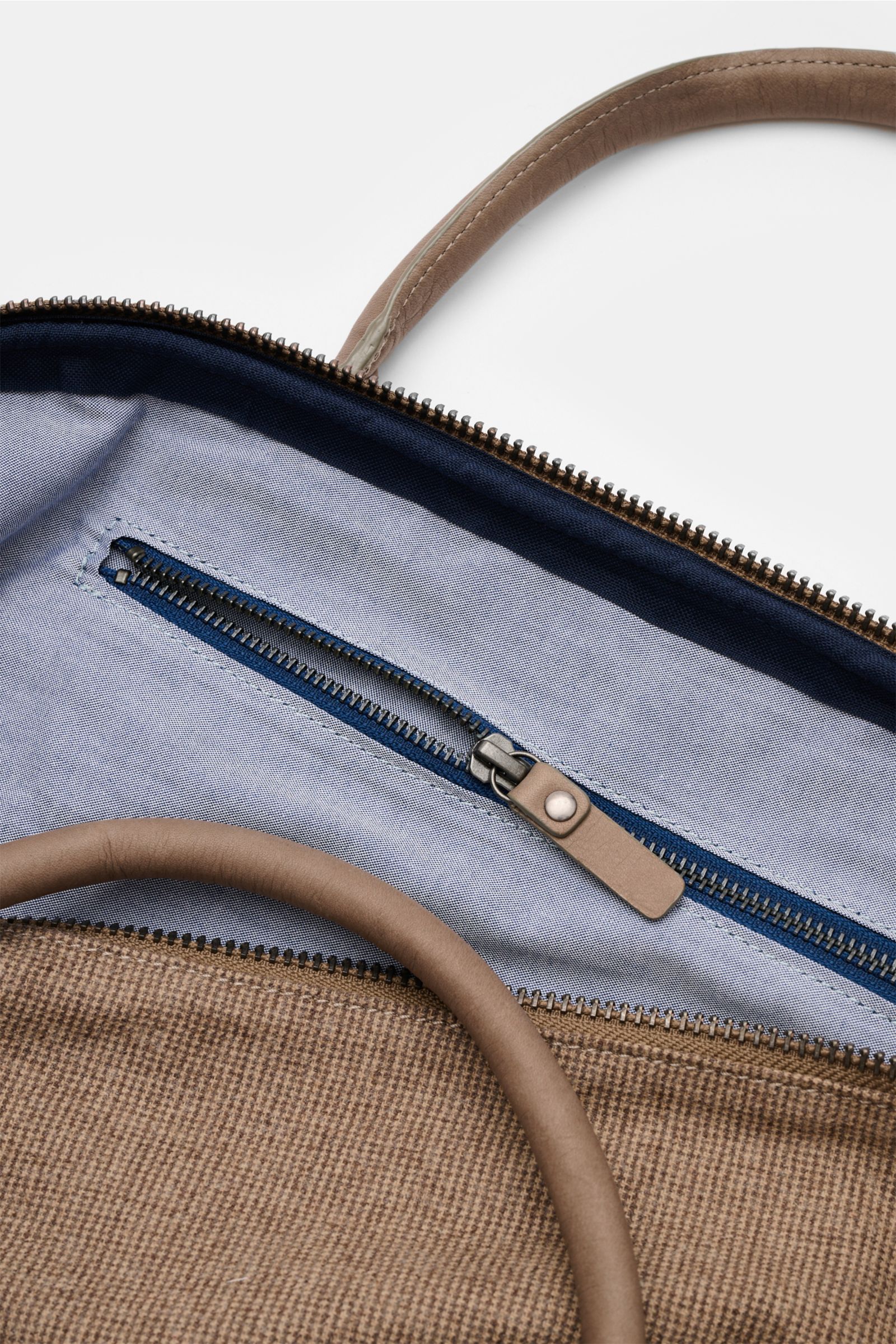 Close-up top view of the open interior of the 04651/ A trip in a bag Weekender '356-Bag Tweed' beige/taupe checked, showing fabric and leather details, internal zip compartment with blue zipper, textile lining, and leather handle.

When holiday time co