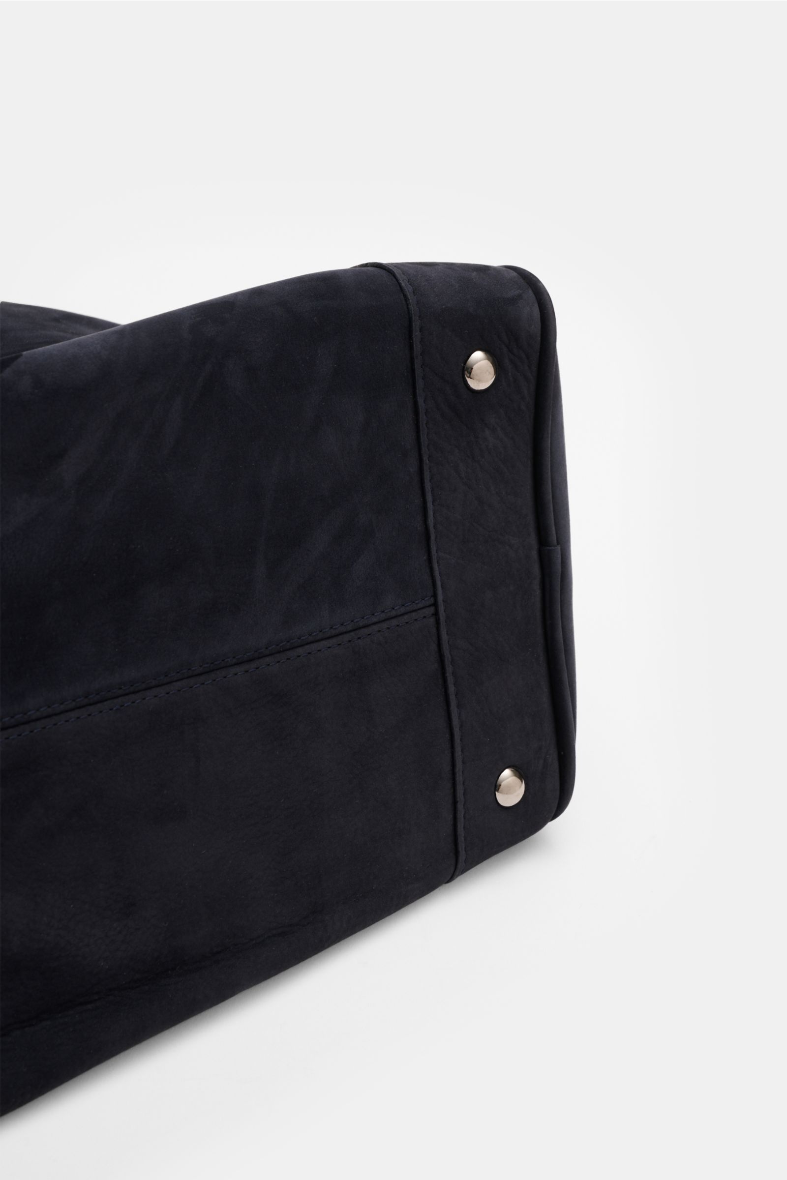 Close-up side view of the bottom corner of the 04651/ A trip in a bag Weekender '356 Bag' navy in soft navy velours leather with silver hardware and protective metal feet.