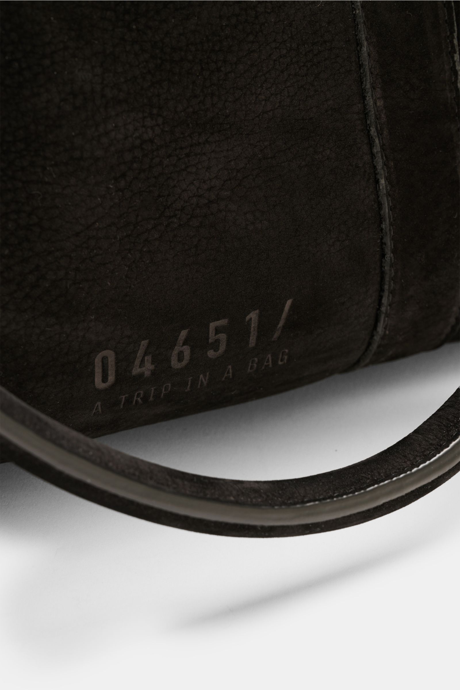 Close-up inside view of the 04651/ A trip in a bag Weekender '3-Day Bag' schwarz showing soft velours leather texture, logo embossing, and part of the adjustable strap, photographed from above at an angle. Der 'Trip in a Bag' kann losgehen: Mit dem größen