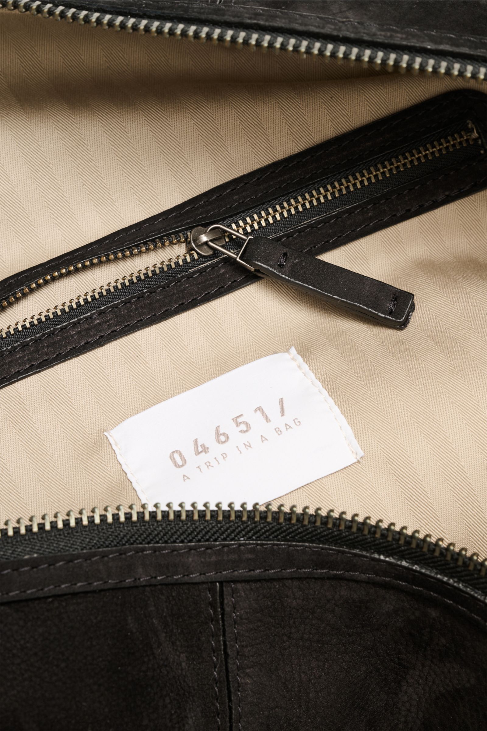 Close-up interior view of the 04651/ A trip in a bag Weekender '3-Day Bag' schwarz showing beige fabric lining, zippered pocket with black leather trim, and logo label.